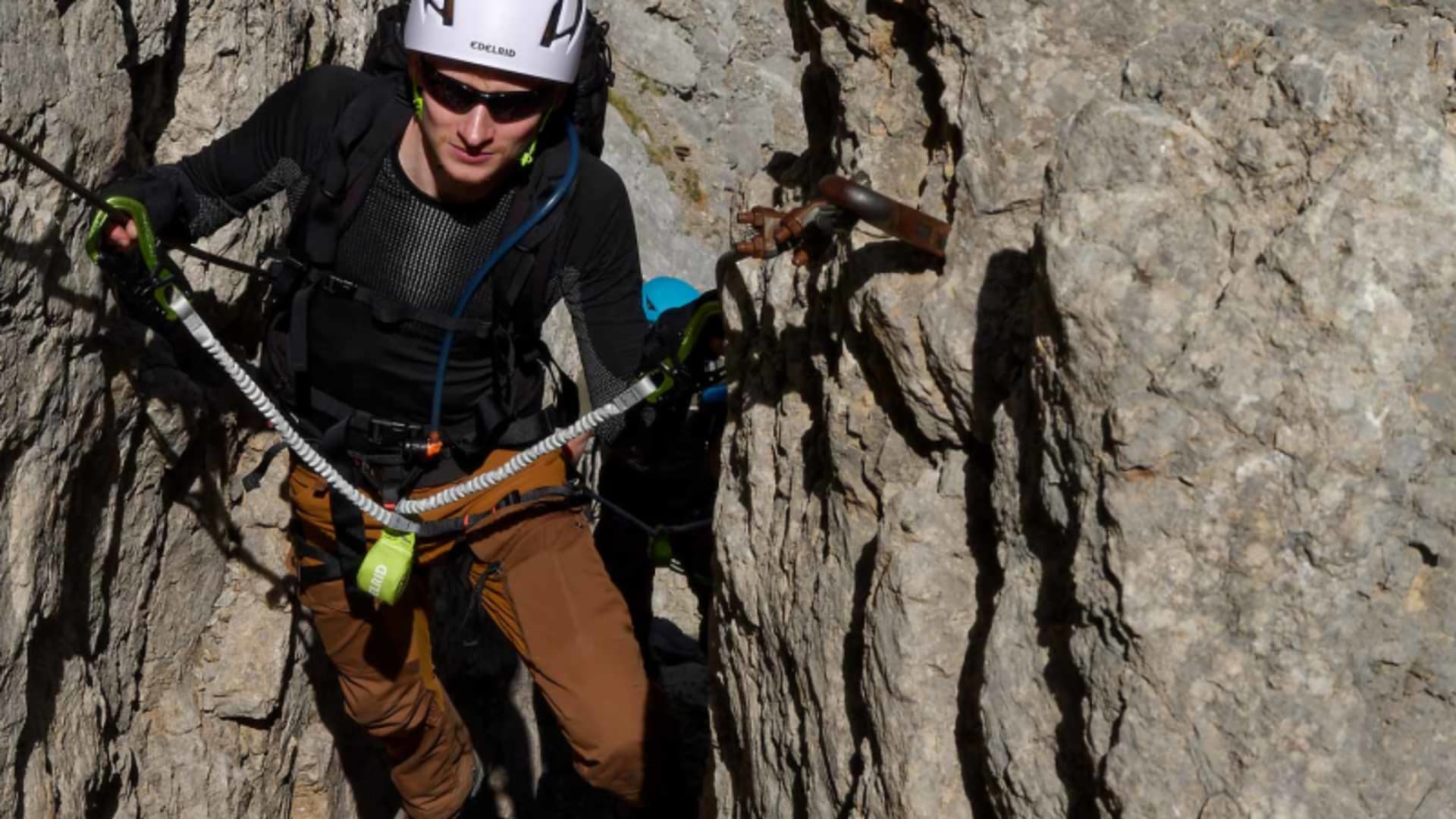 Klettersteiggeher mit Helm und Klettersteigset in einer engen Felsspalte am Mittenwalder Höhenweg im Karwendel.