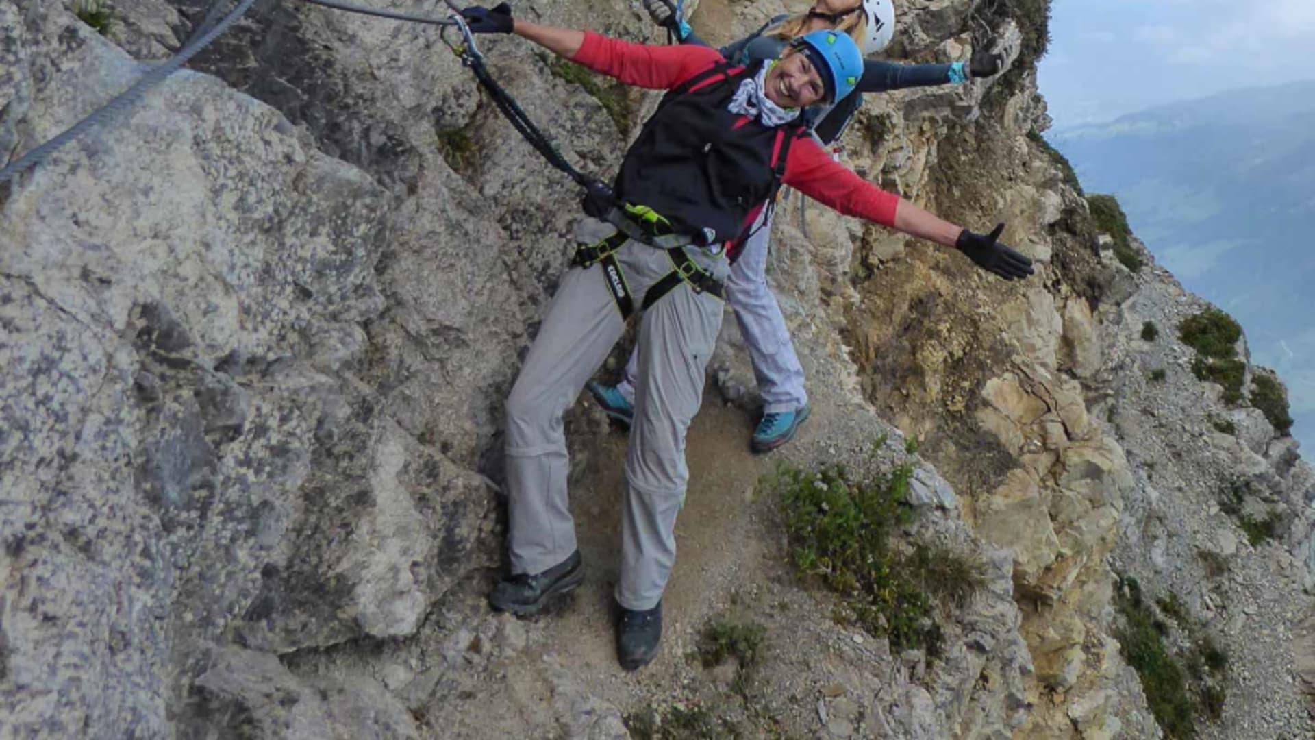 Klettersteig am Iseler: zwei Klettersteiggeher mit Helm und Klettergurt gesichert am Drahtseil einer Kalksteinwand.