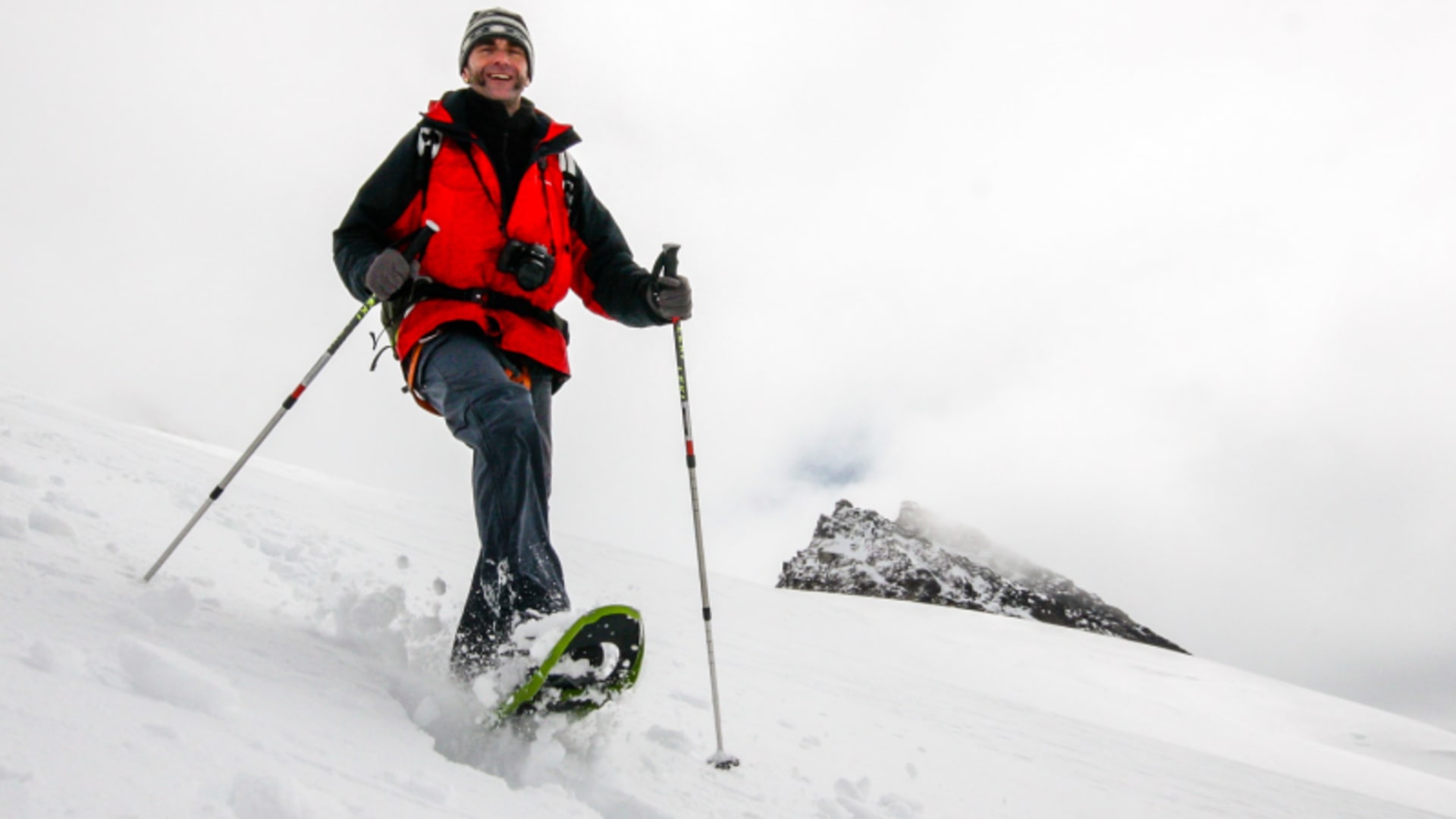 Zwei Schneeschuhwanderer mit Teleskopstöcken steigen auf einem verschneiten Hang in den Hohen Tauern im Winter auf.