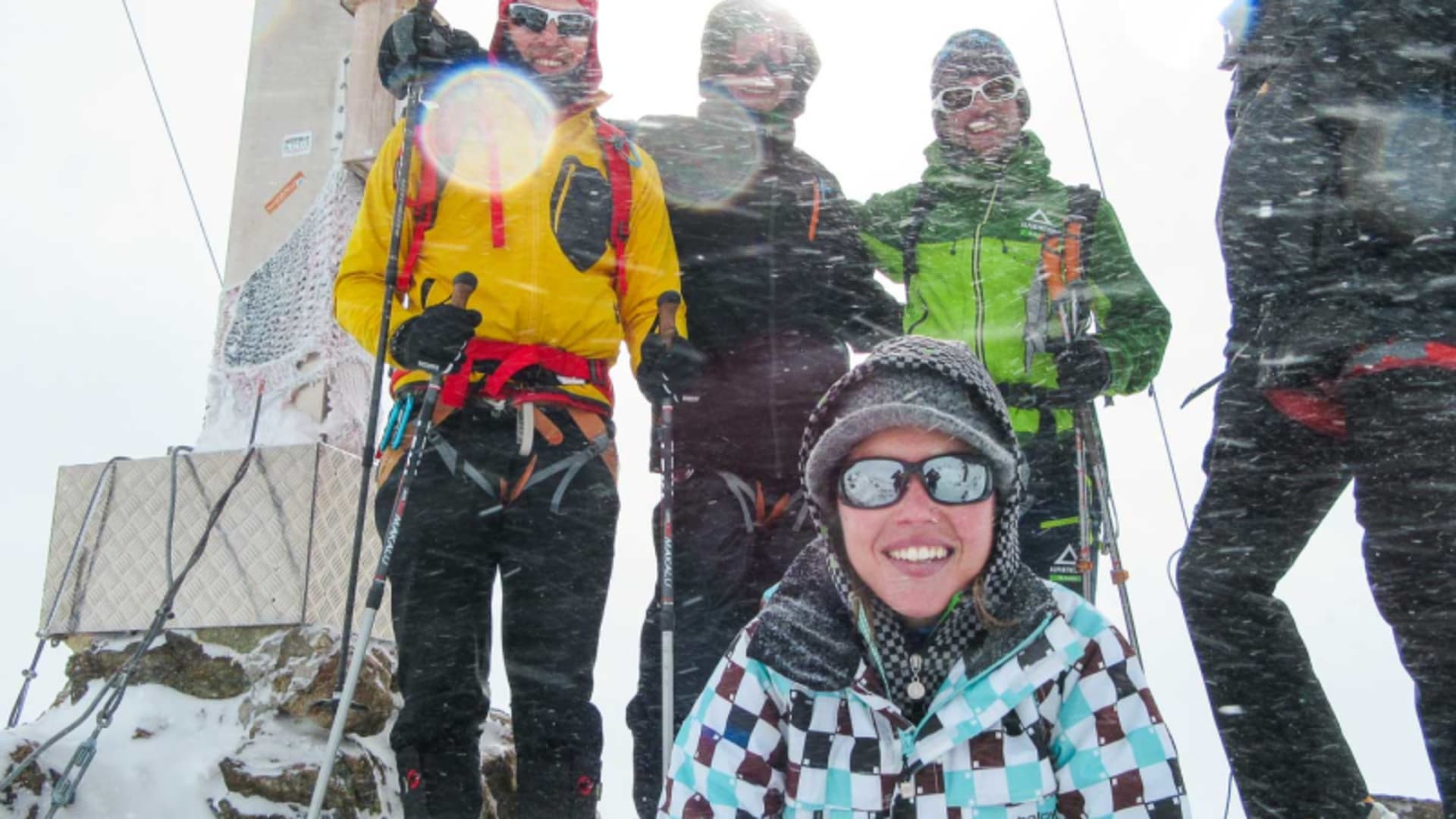 Fünf Schneeschuhwanderer posieren bei Schneetreiben auf einem felsigen Gipfel in der Silvretta.