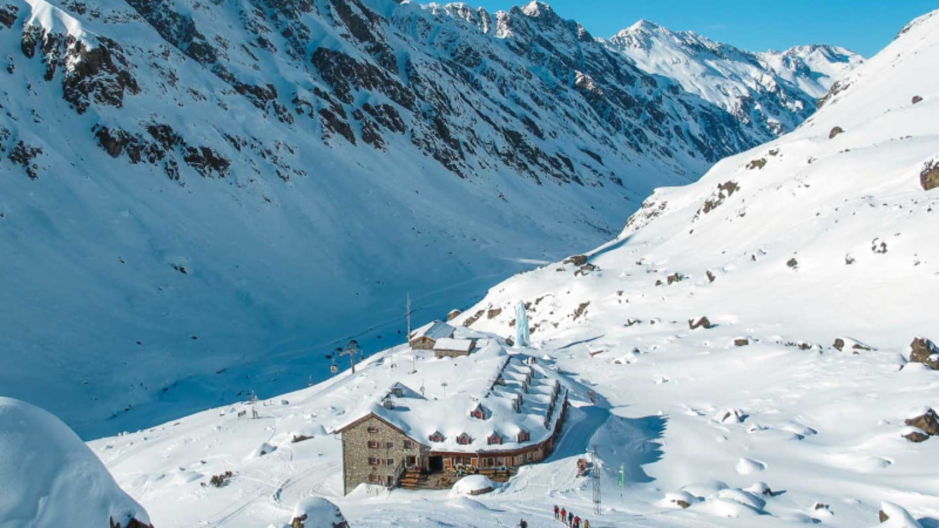 Schneeschuhtour zur Jamtalhütte: Natursteingebäude mit rotem Fensterladen im verschneiten Hochtal der Silvretta.