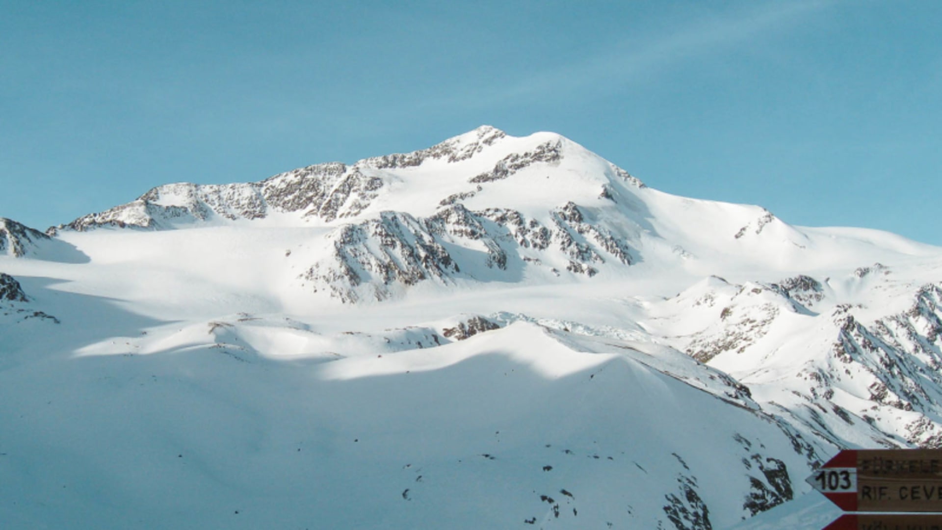 Skitour im Ortlergebiet: schneebedeckter Gipfelaufbau mit Gletscherplateau und Wegweiser zum Rifugio Cevedale.