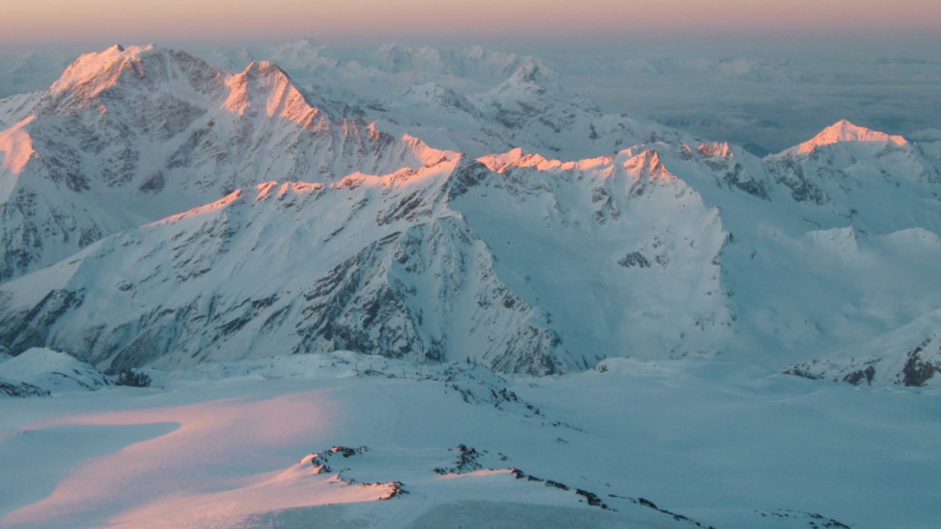 Gruppe von Skitourengehern auf dem Gletscherplateau am Elbrus im Morgen- oder Abendrot des Kaukasus.