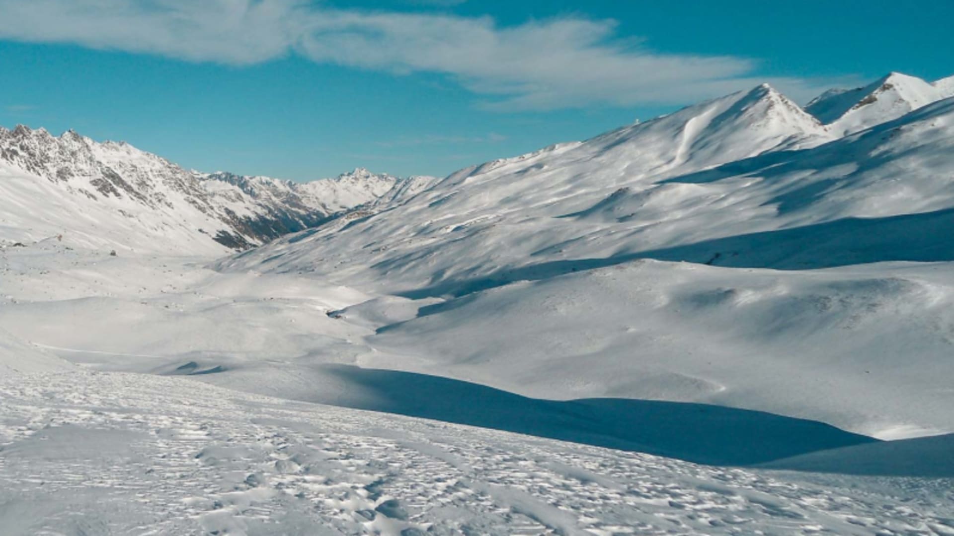 Verschneites Hochtal in der Silvretta mit felsigem Gebirgskamm und windgeprägter Schneeoberfläche im Winter.