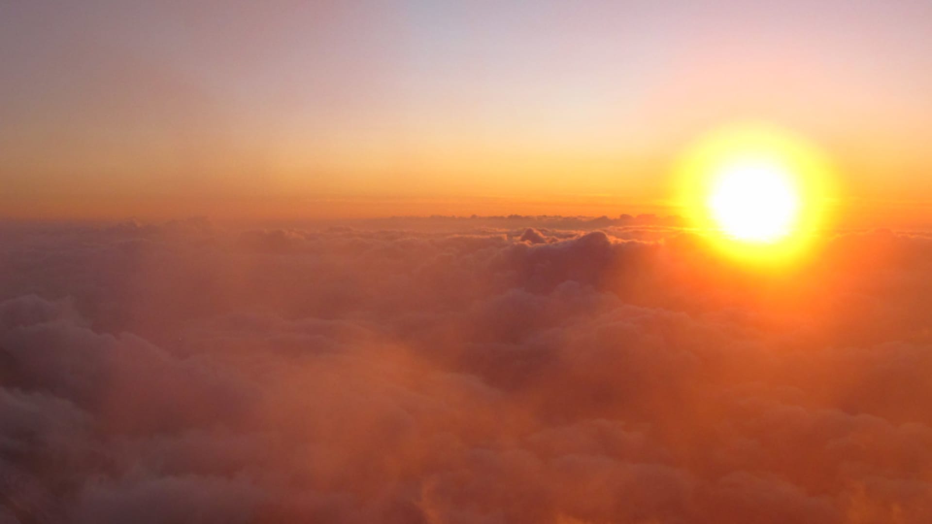 Skitour am Mont Blanc: Sonnenuntergang über einer leuchtenden Wolkendecke, aufgenommen von einem hochalpinen Standort
