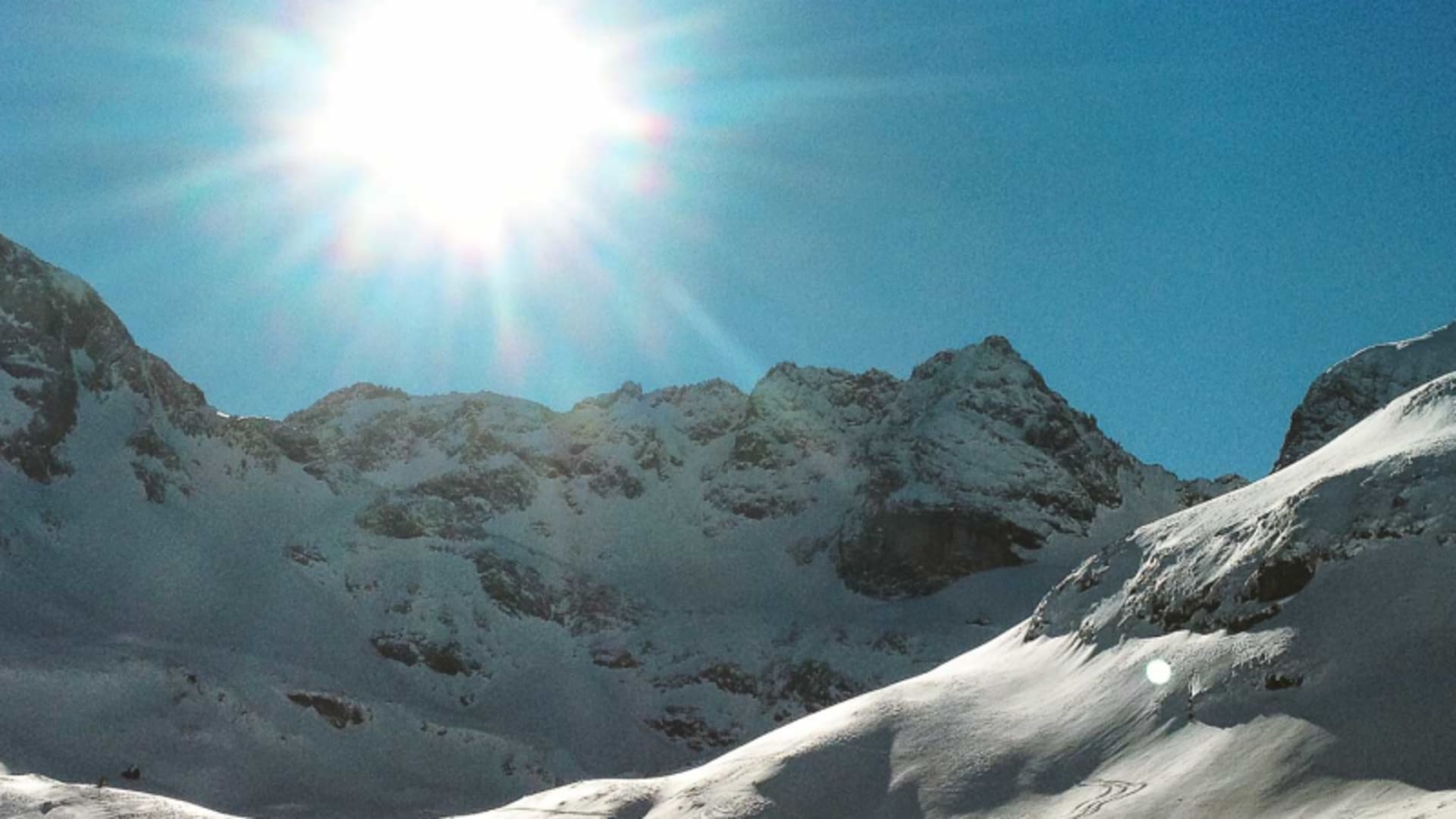 Skitour Naturpark Fanes: spitzer Gipfel mit Gipfelkreuz und verschneiter Felskamm unter intensiv blauem Winterhimmel.