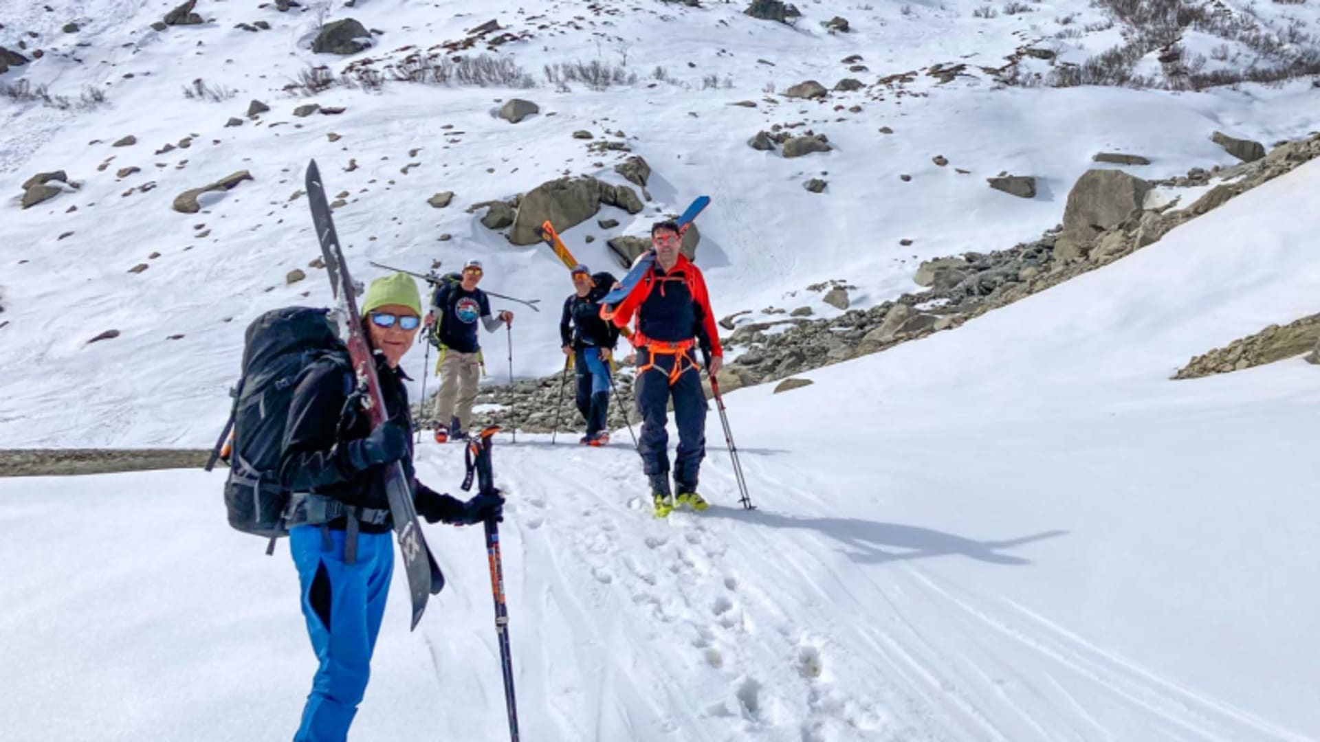 Drei Skitourengeher tragen ihre Skier auf der Schulter durch eine verschneite Rinne in den Urner Alpen.