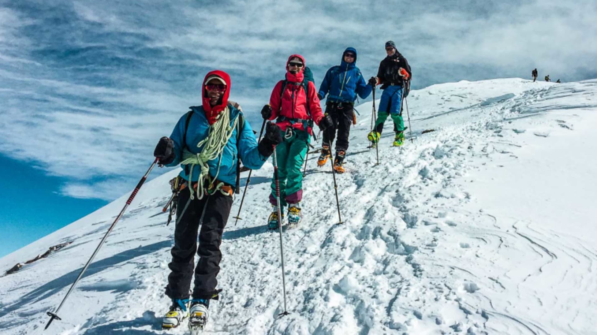 Vier Skitourengeher steigen mit Steigeisen und Pickel in Einerkolonne den verschneiten Steilhang zur Wildspitze im Ötztal auf.