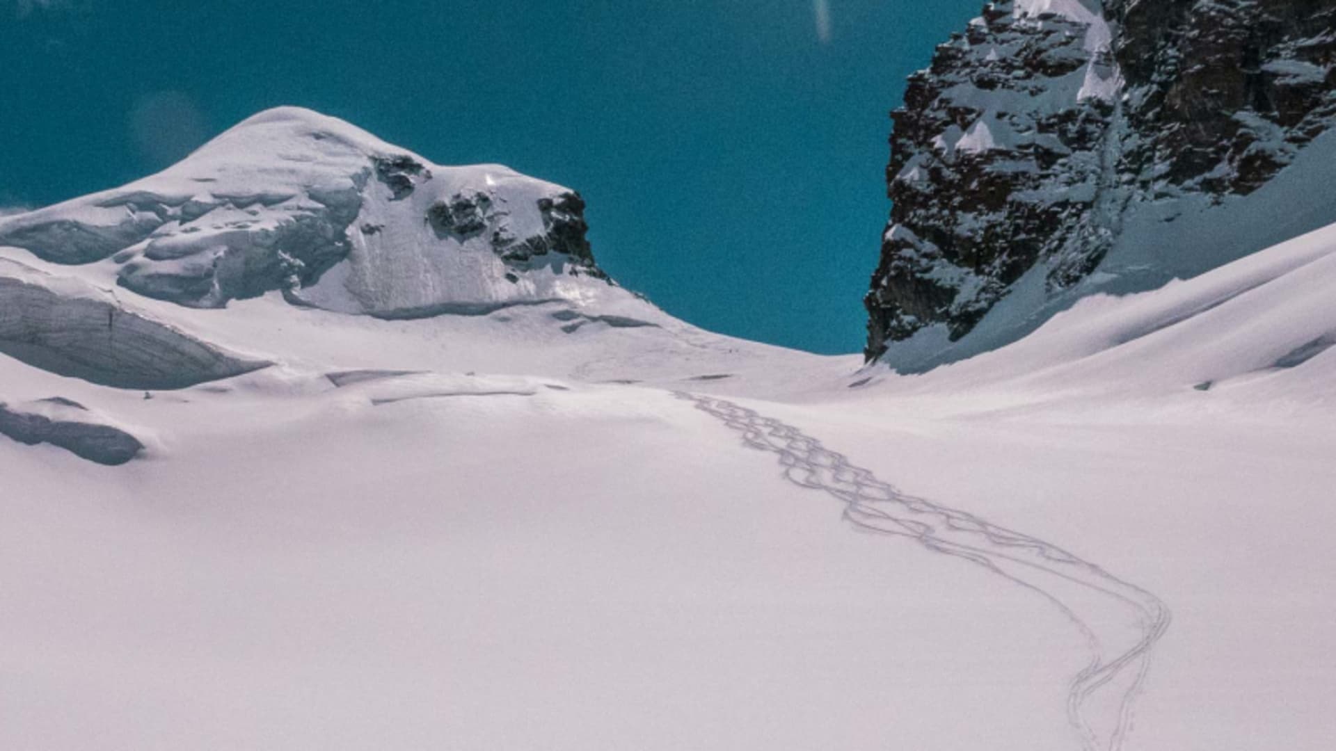 Skispuren in geschwungenen Bögen auf dem Gletscherhang zur Monterosahütte im Wallis, kein Skitourengeher sichtbar.