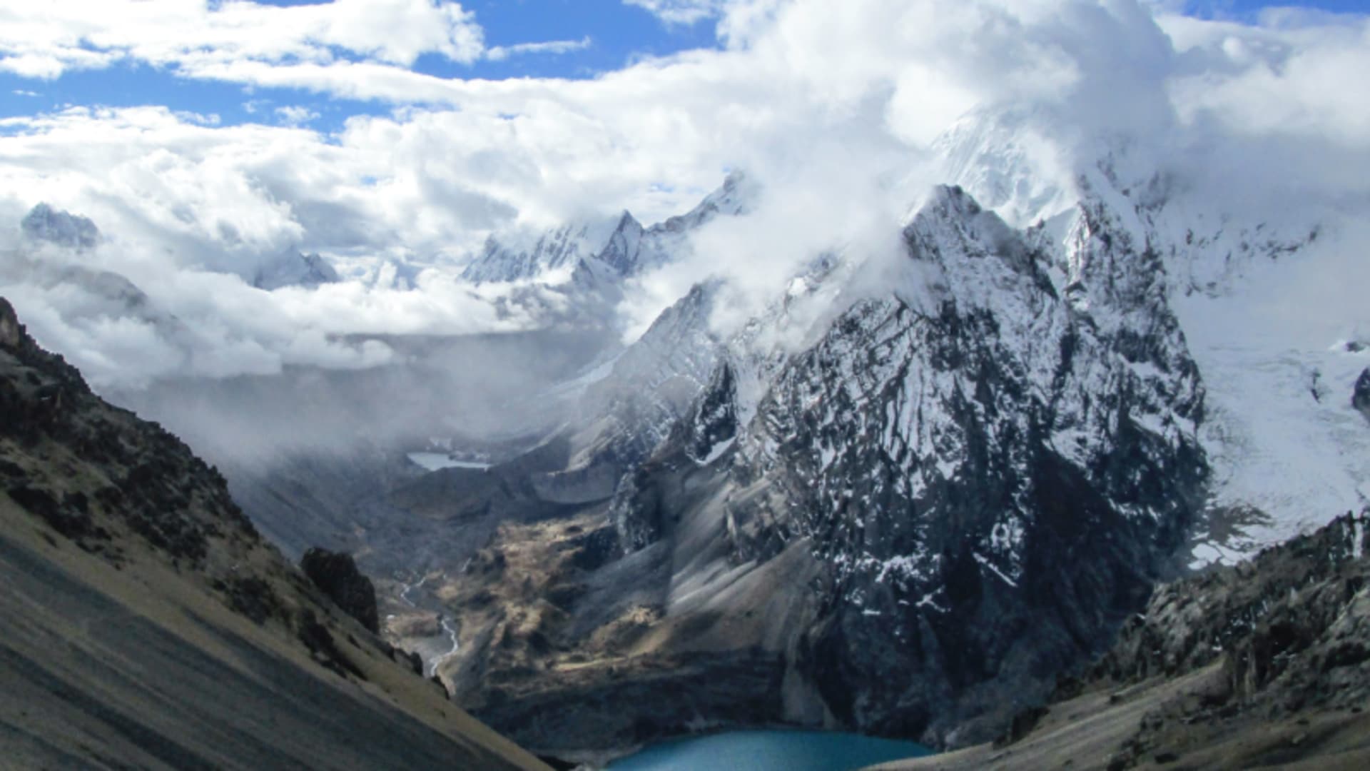 Blick vom Hang auf den türkisfarbenen Mitucocha See im glazialen Hochtal der Cordillera Huayhuash.