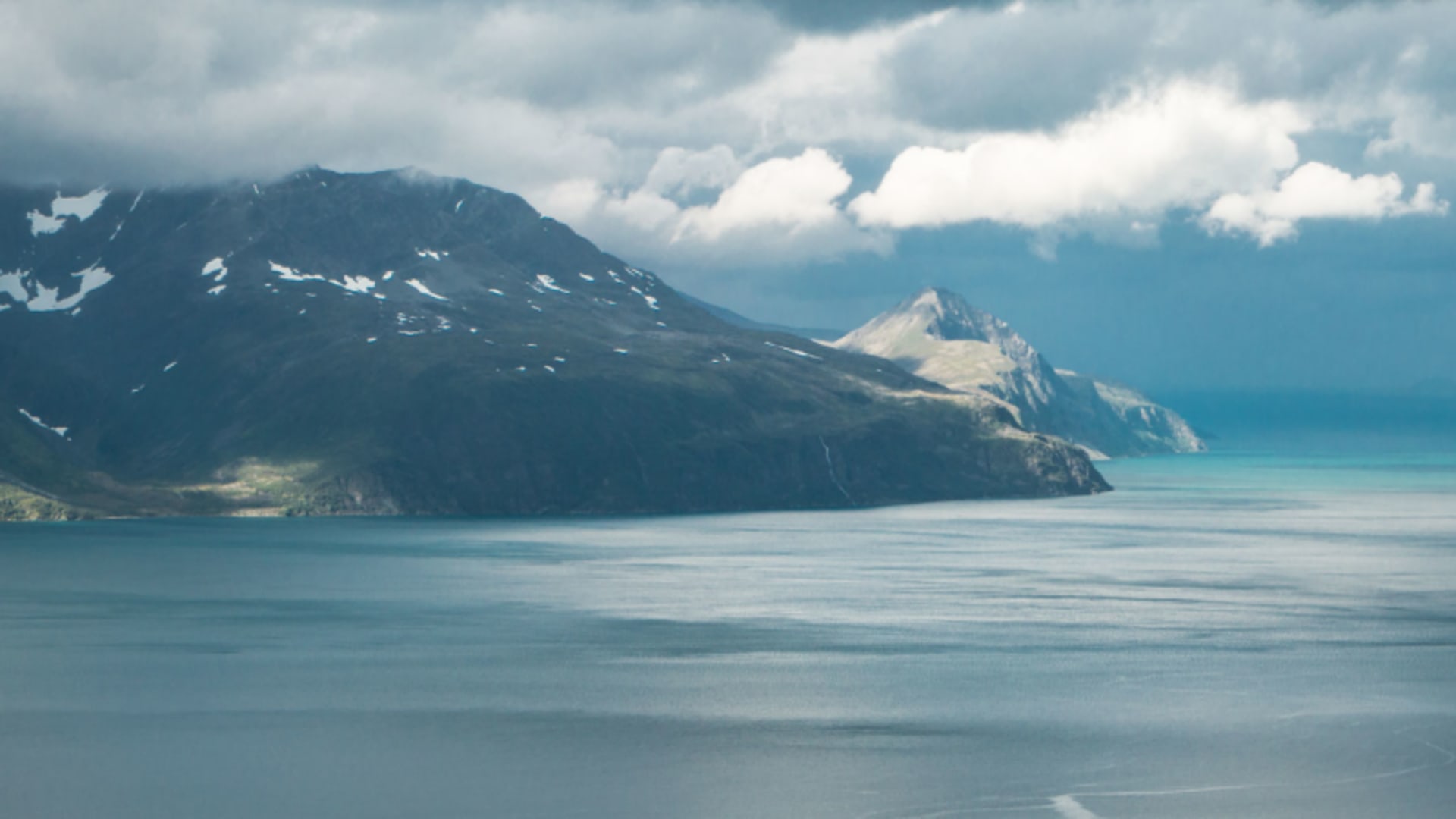 Panoramablick vom Storhaugen auf den Fjord und die Lyngeninsel mit schneebedeckten Berggipfeln in den Lyngenalpen.