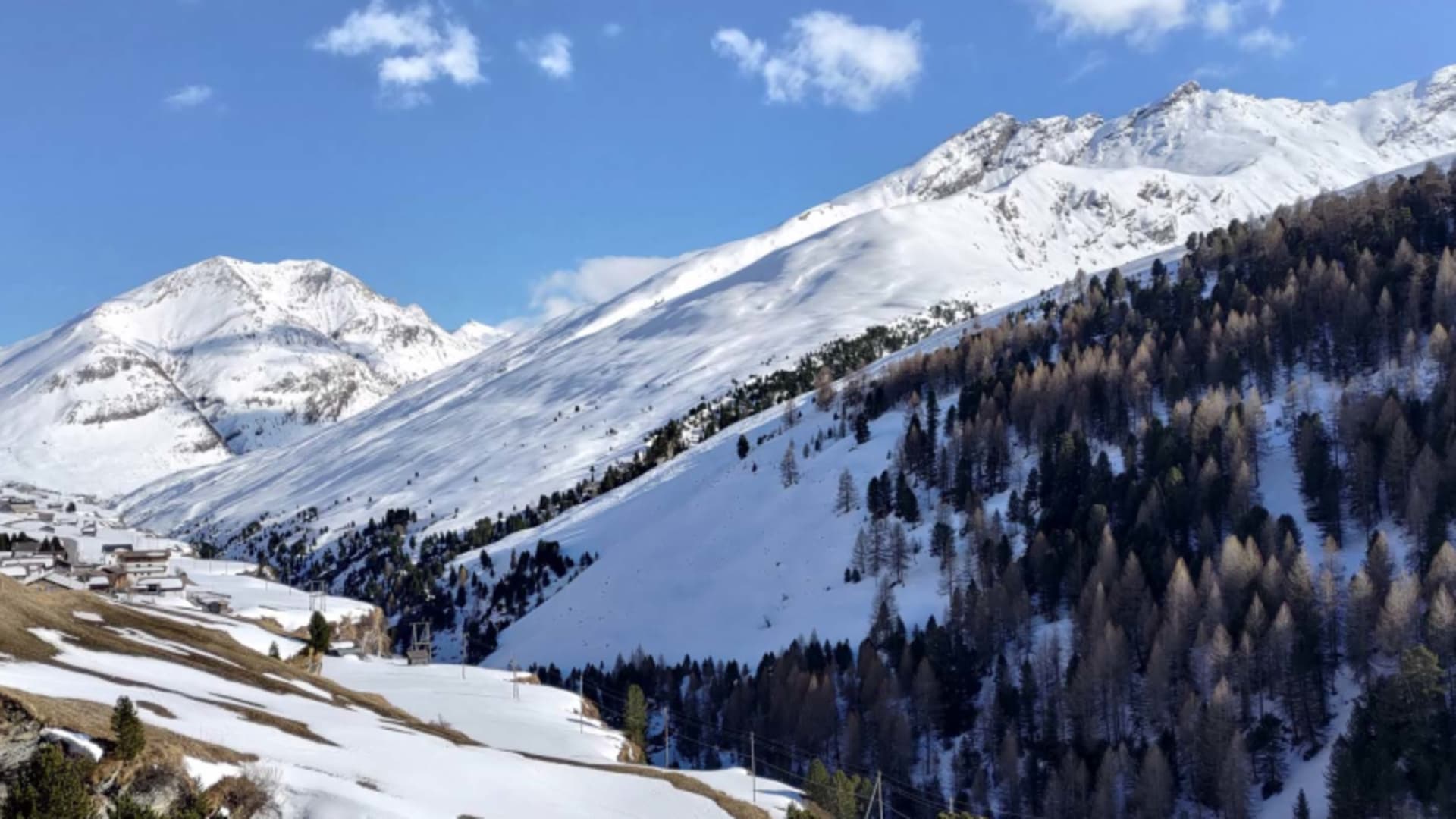 Winterwanderung im Averstal: verschneites Hochtal mit kleiner Bergsiedlung und schneebedeckten Gipfeln im Hintergrund.