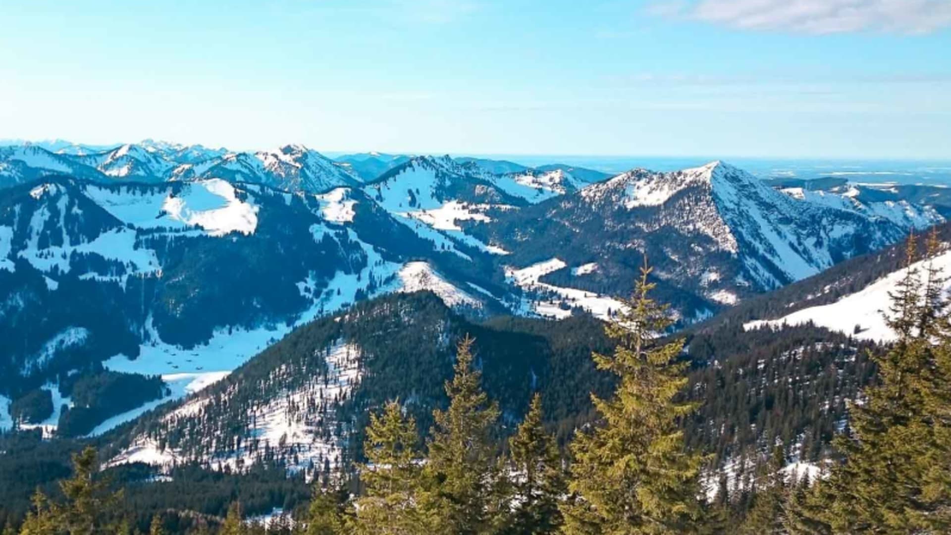 Winterwanderung im Spitzingsee-Gebiet: schneebedecktes Bergpanorama mit Nadelwäldern und Gipfelkette im Winter.