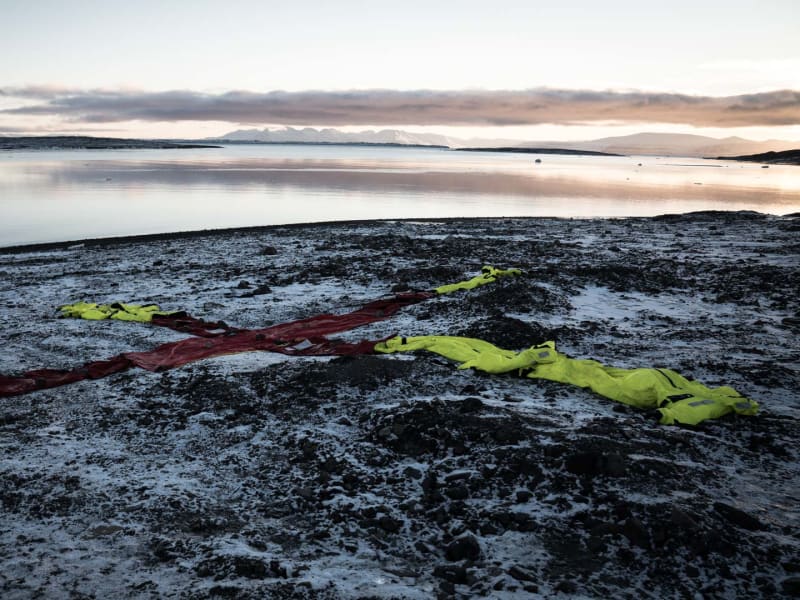 Rotes X-Kreuz mit neongelben Survival-Suits als Suchmarkierung an arktischer Küste im Winter.