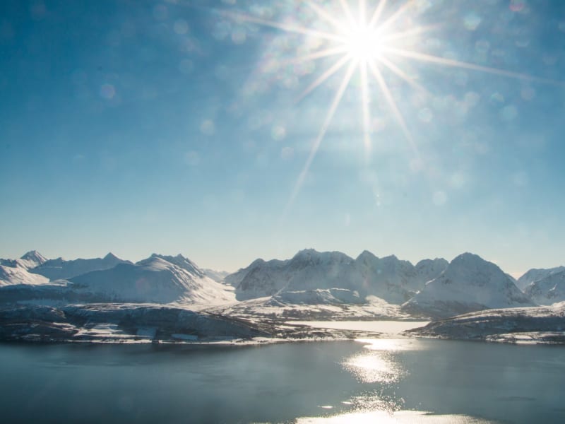 Skitour Ski and Sail Lyngen: Blick über den Fjord auf die schneebedeckten Gipfel der Lyngenalpen in Norwegen.