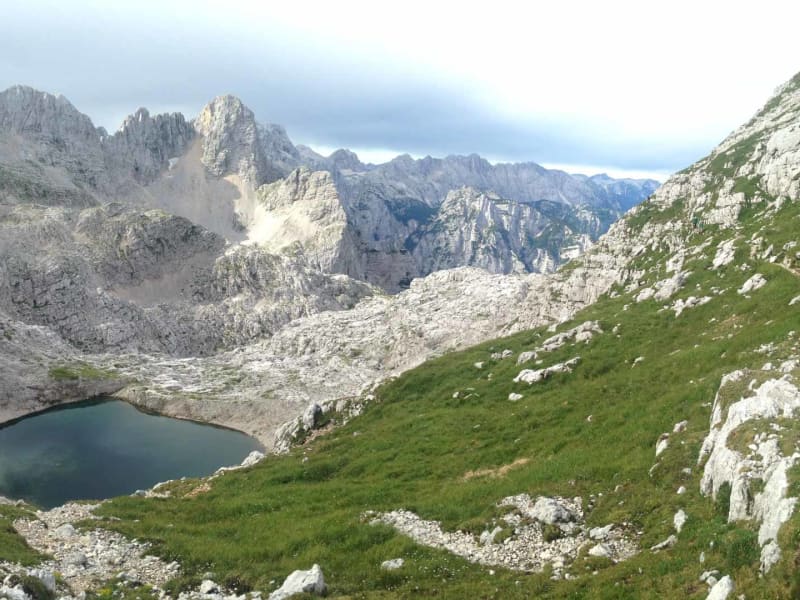 Bergtour in den slowenischen Bergen: Hochgebirgssee in einem Kalksteinkar mit Felsgipfeln im Hintergrund.