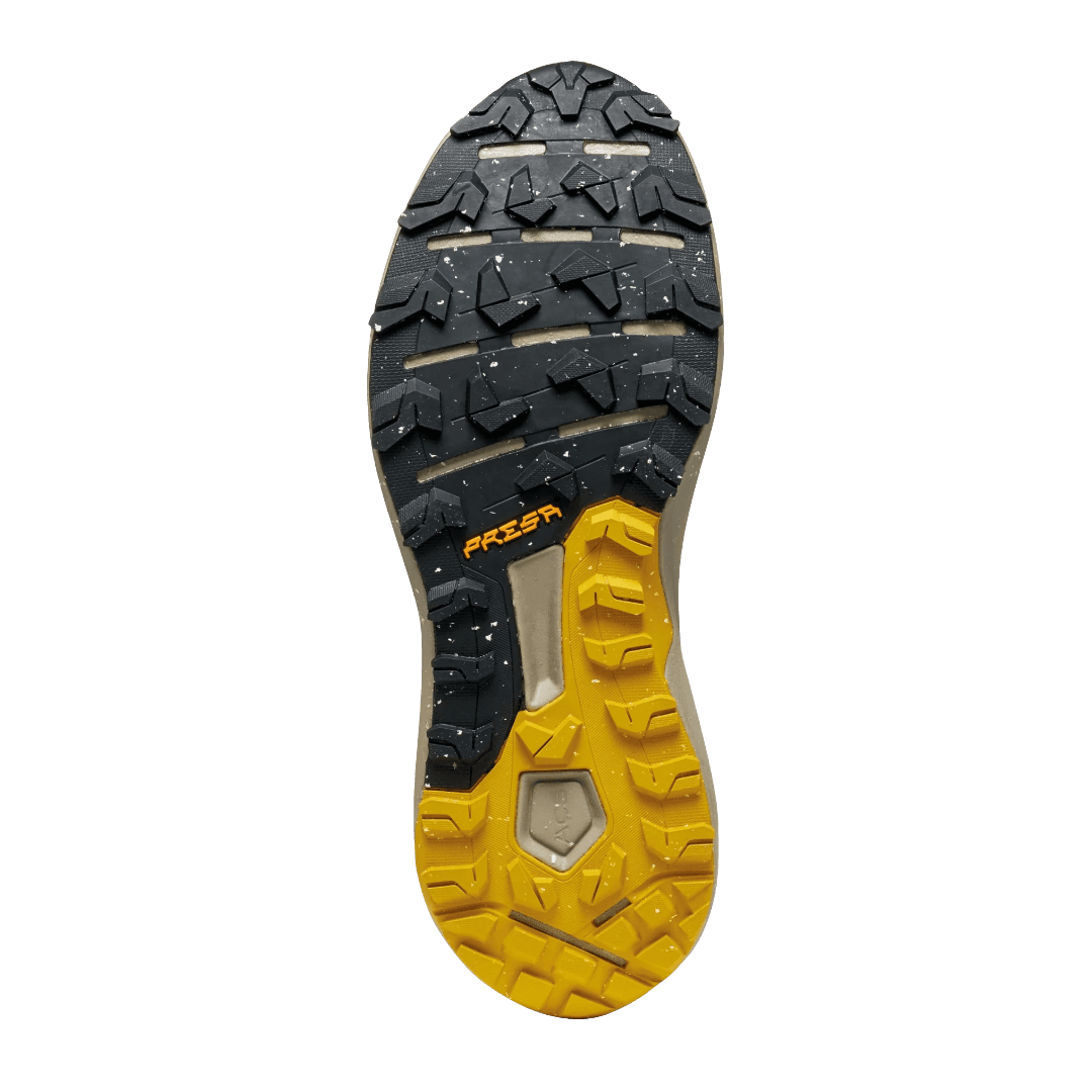 Nahaufnahme der Profilsohle eines Trailrunning-Schuhs mit geometrischem Stollenmuster in Schwarz und Gelb.