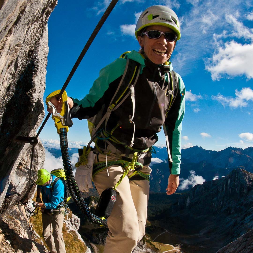 Klettersteigkurse mit Bergführer: Person mit Edelrid-Helm und Klettersteigset an steilem Kalkfels bei sommerlicher Bergtour