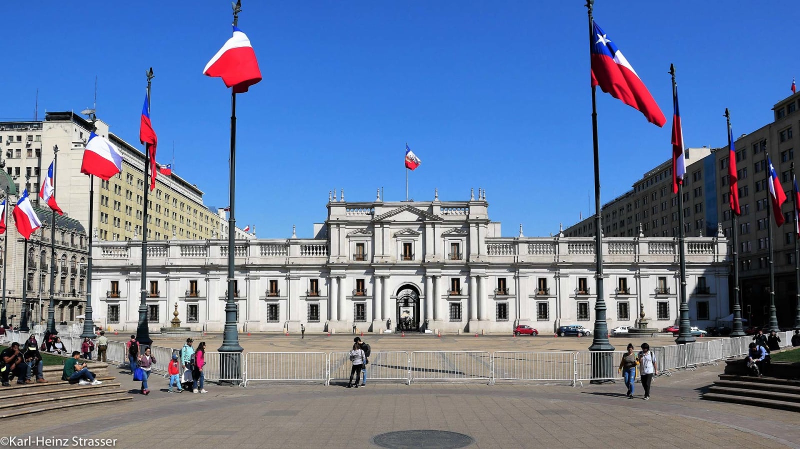 Skitour Santiago Chile: Präsidentenpalast mit chilenischen Flaggen, gepflastertem Vorplatz und Besuchern bei sonnigem Wetter.