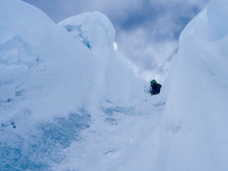 Expedition Alpamayo: ein Höhenbergsteiger steigt durch einen Eisspalt im Gletschergelände am Alpamayo auf.