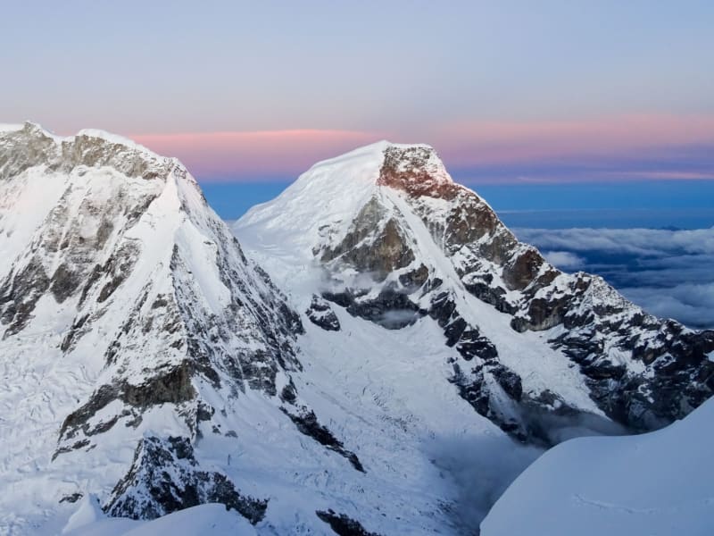 Expedition Huascarán: Panorama der beiden Gipfel mit Gletscherplateau im Morgenlicht über dem Wolkenmeer.