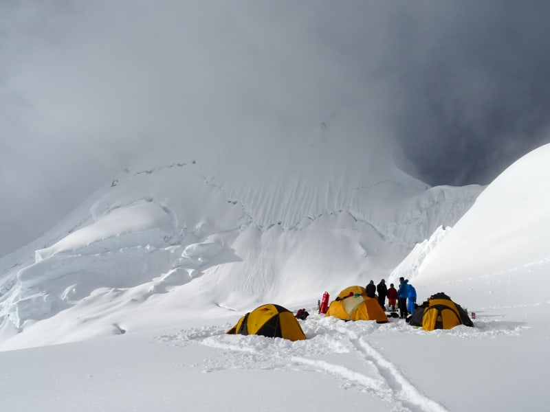 Expedition Alpamayo: vier Zelte und fünf Höhenbergsteiger im Hochlager auf schneebedecktem Gletscher am Alpamayo.