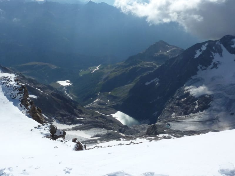 Hochtour am Piz Palü: Zwei Bergsteiger steigen einen steilen Schneehang ab, im Hintergrund öffnet sich das Tal mit Gletscherbereich.
