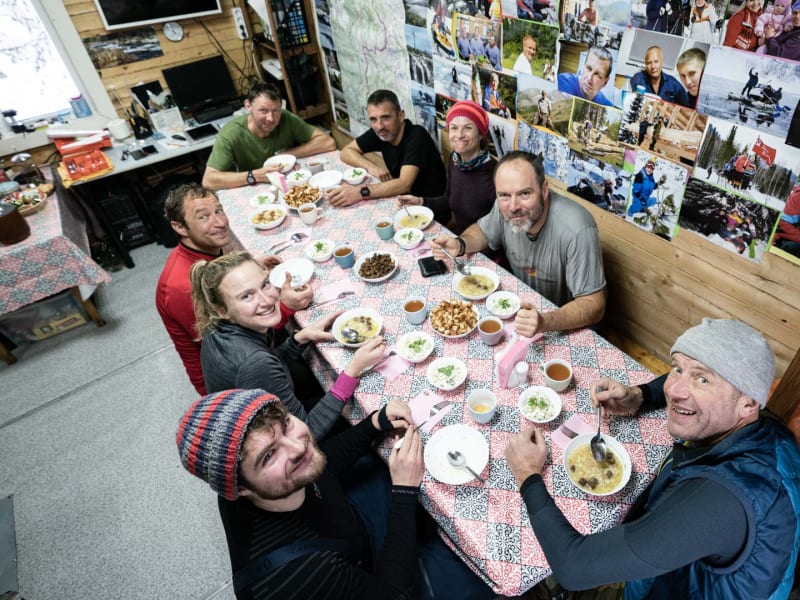Skitourengeher beim gemeinsamen Essen in einer Basislager-Hütte in Sibirien, Russische Föderation, im Winter.