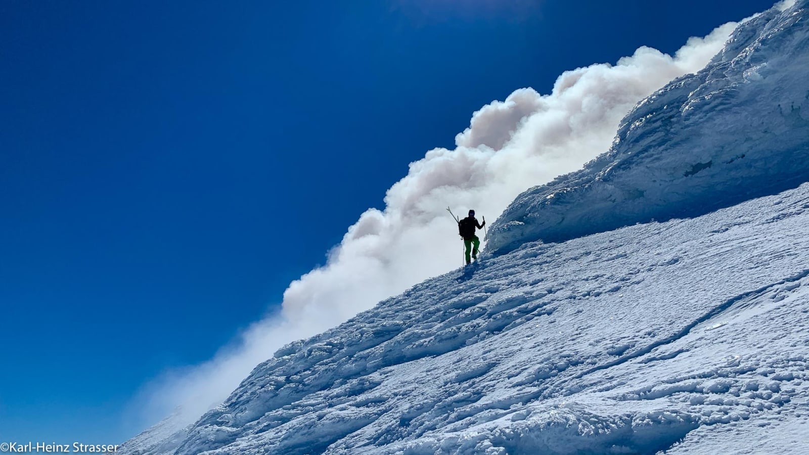 Bergtour am Schneehang – doch besser von der anderen Seite: Skibergsteiger im Aufstieg, hinter ihm bricht Windschnee