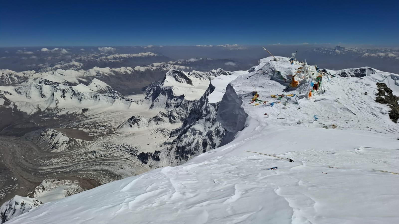 Bergtour auf den Muztagh Ata: felsiger Gipfelaufbau mit Gebetsfahnen, Schneestrukturen und Gletscherpanorama in China.