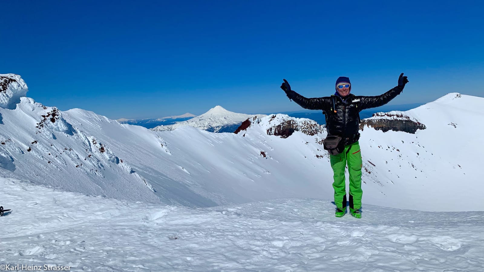 Bergsteiger auf dem schneebedeckten Gipfelplateau des Lonquimay mit ausgestreckten Armen im Winter.