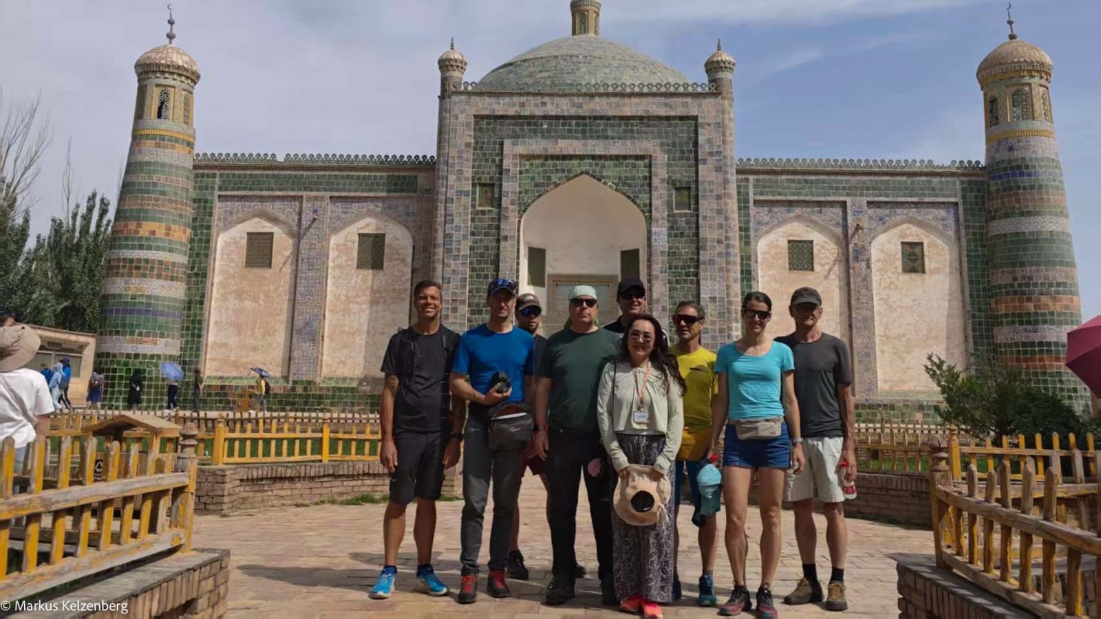 Stadtbesichtigung Kashgar: Neun Bergsteiger posieren vor einem islamischen Kuppelbau mit türkisen Keramikfliesen.