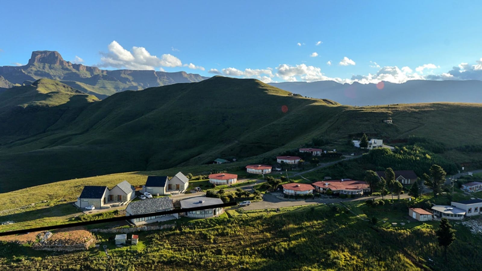 Drohnenaufnahme der Unterkunftsanlage Witsieshoek mit Rundbau-Gebäuden vor tafelförmigen Bergmassiven.