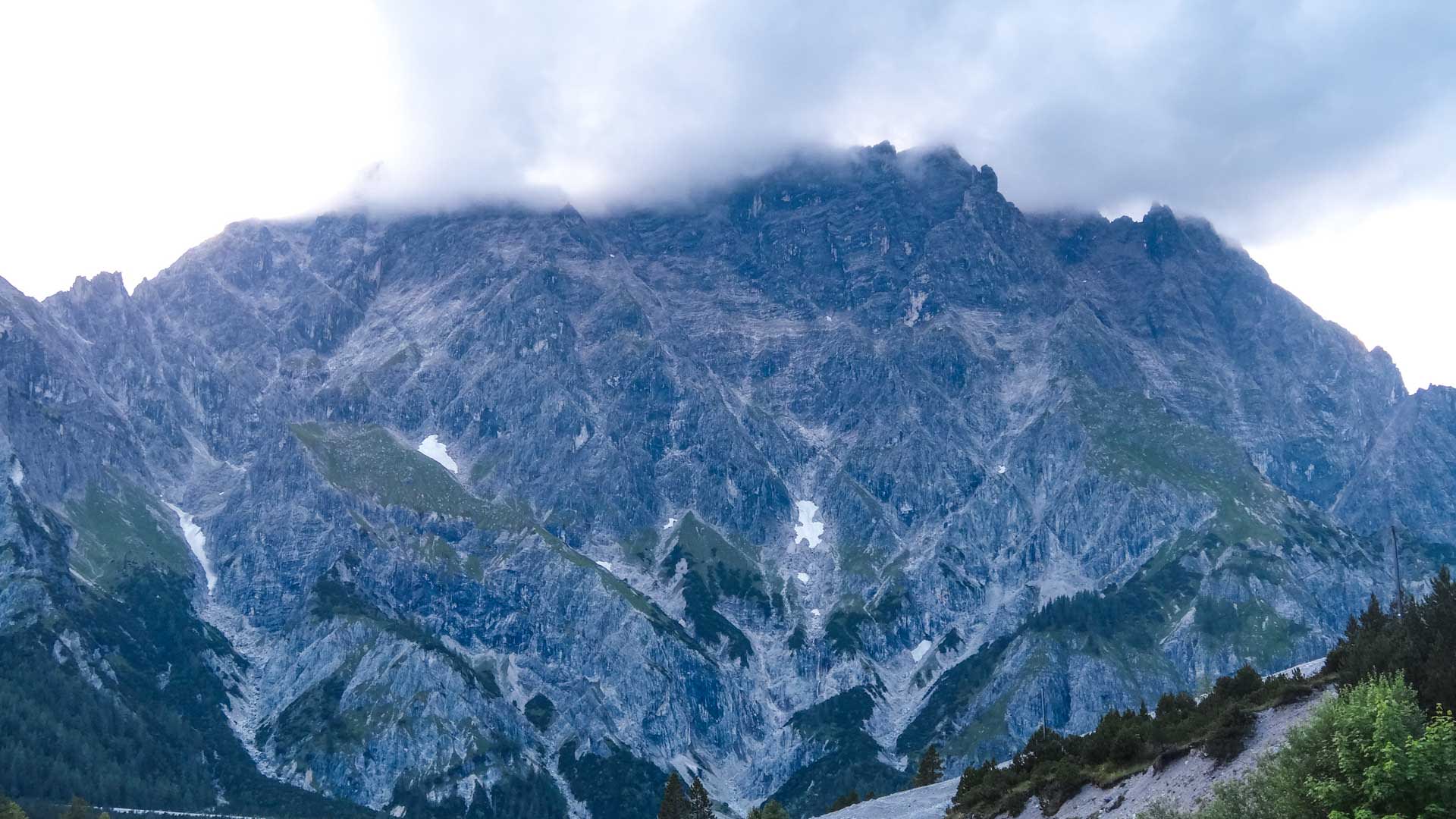Bergwanderung im wilden Wimbachtal: senkrechte Kalkfelswand mit Schneefeldern in Rinnen, Nationalpark Berchtesgaden.