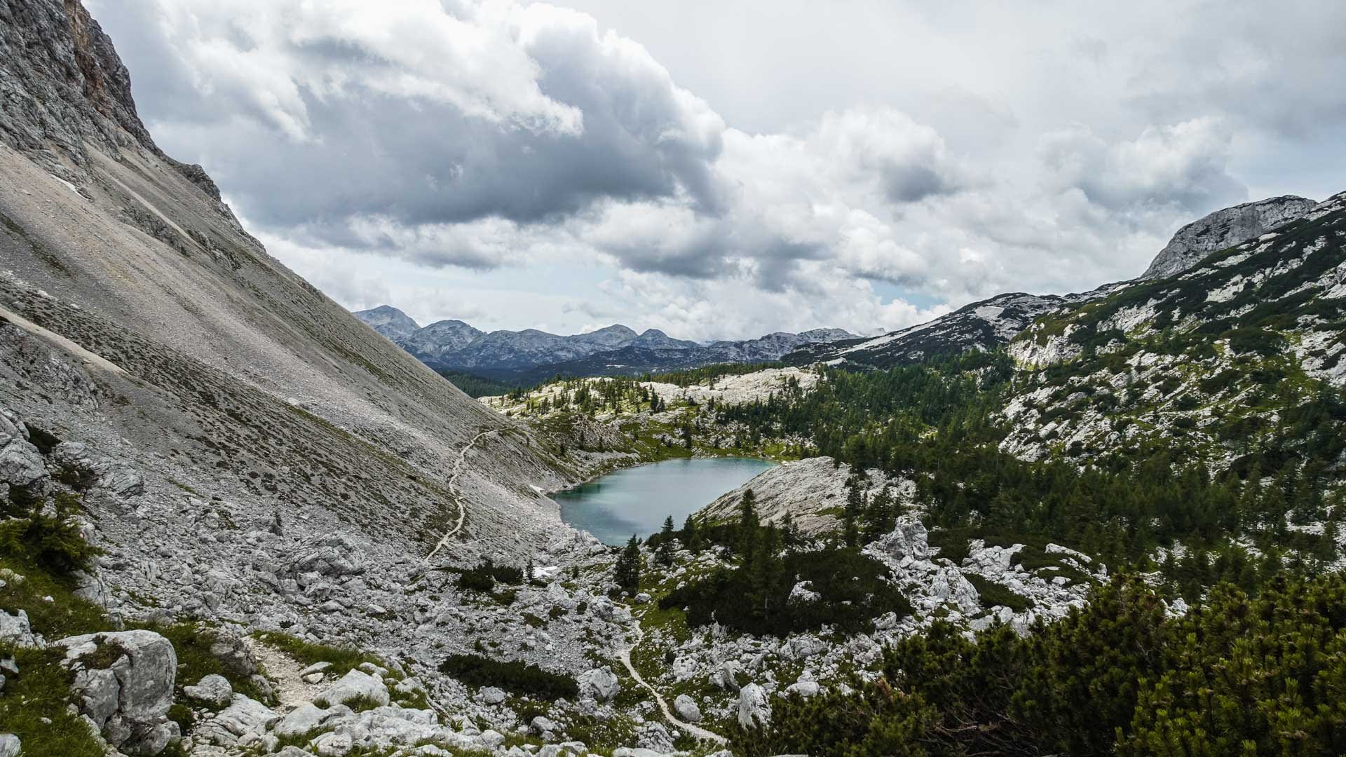 Bergwanderung im Sieben-Seen-Tal: Blick auf den türkisblauen Nierensee mit Kalksteinhang und Wanderpfad in Slowenien.