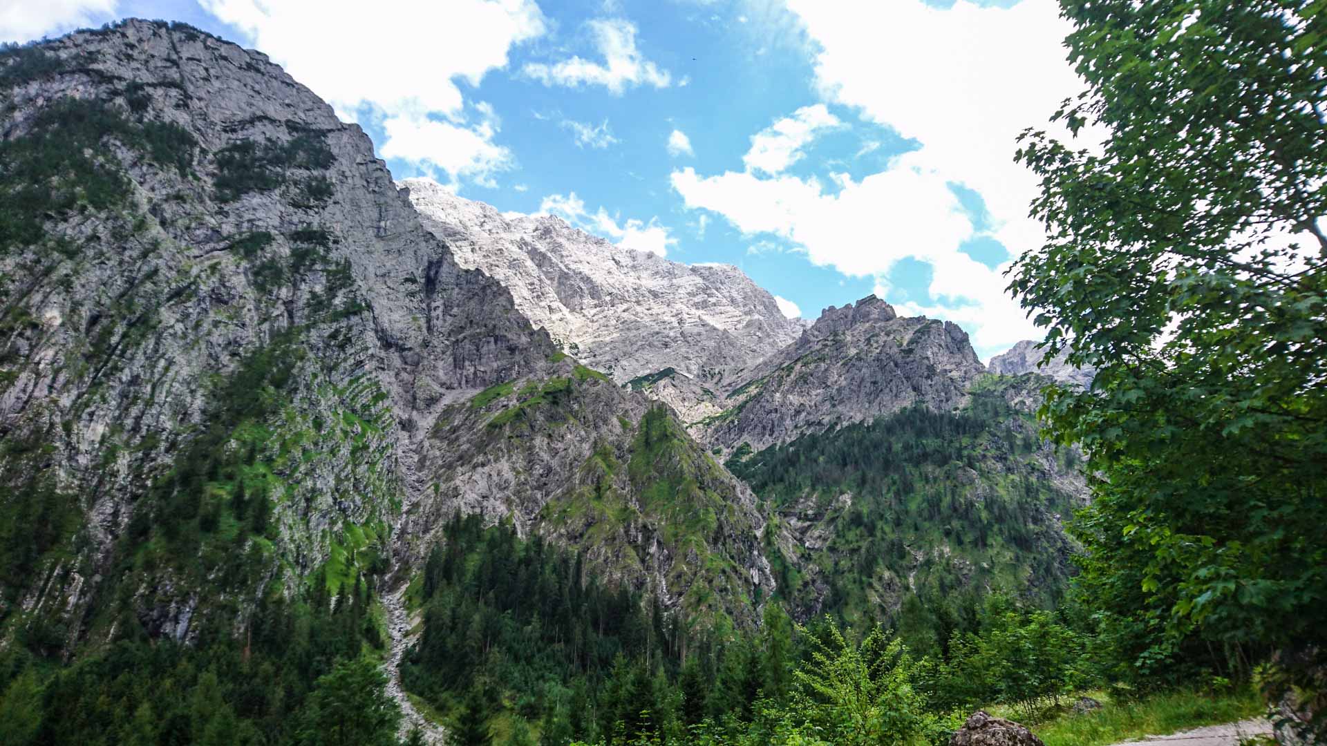 Bergwanderung im Wimbachtal: Blick auf die helle Kalksteinwand der Watzmannüberschreitung über bewaldeten Talhängen.