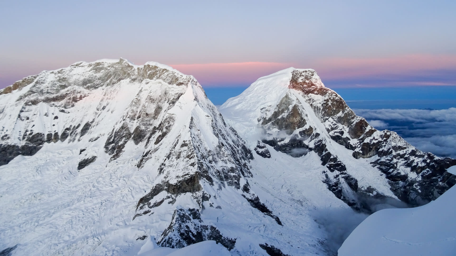 Expedition Huascarán: Panorama der beiden Gipfel mit Gletscherplateau im Morgenlicht über dem Wolkenmeer.