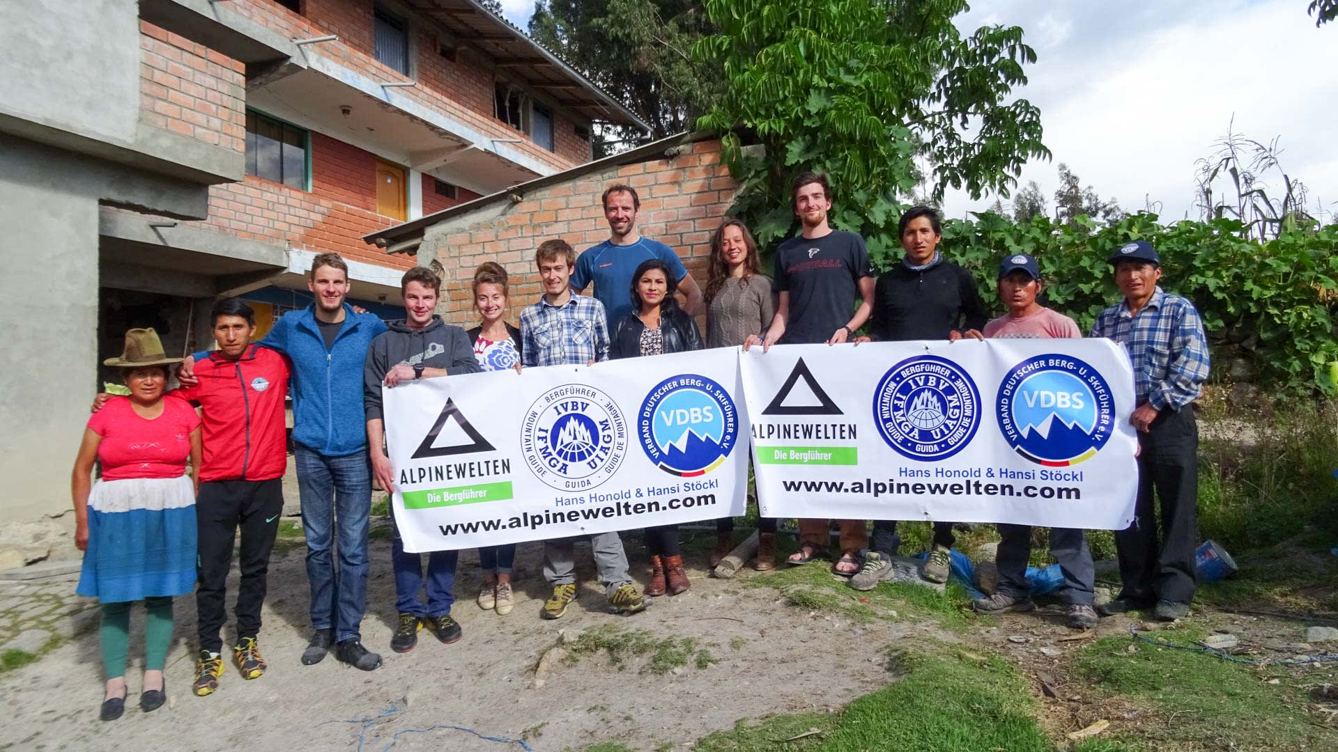 Expedition Alpamayo & Huascaran 2017: zwölf Personen der Expeditionsmannschaft mit Alpine Welten-Banner vor Backsteingebäude.
