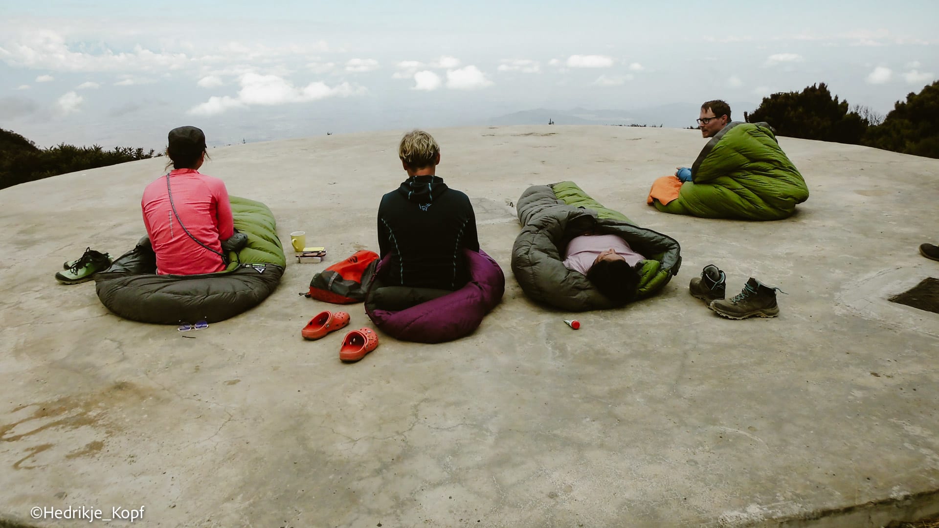 Vier Höhenbergsteiger ruhen in Schlafsäcken auf der Saddlehut-Plattform am Kilimanjaro.