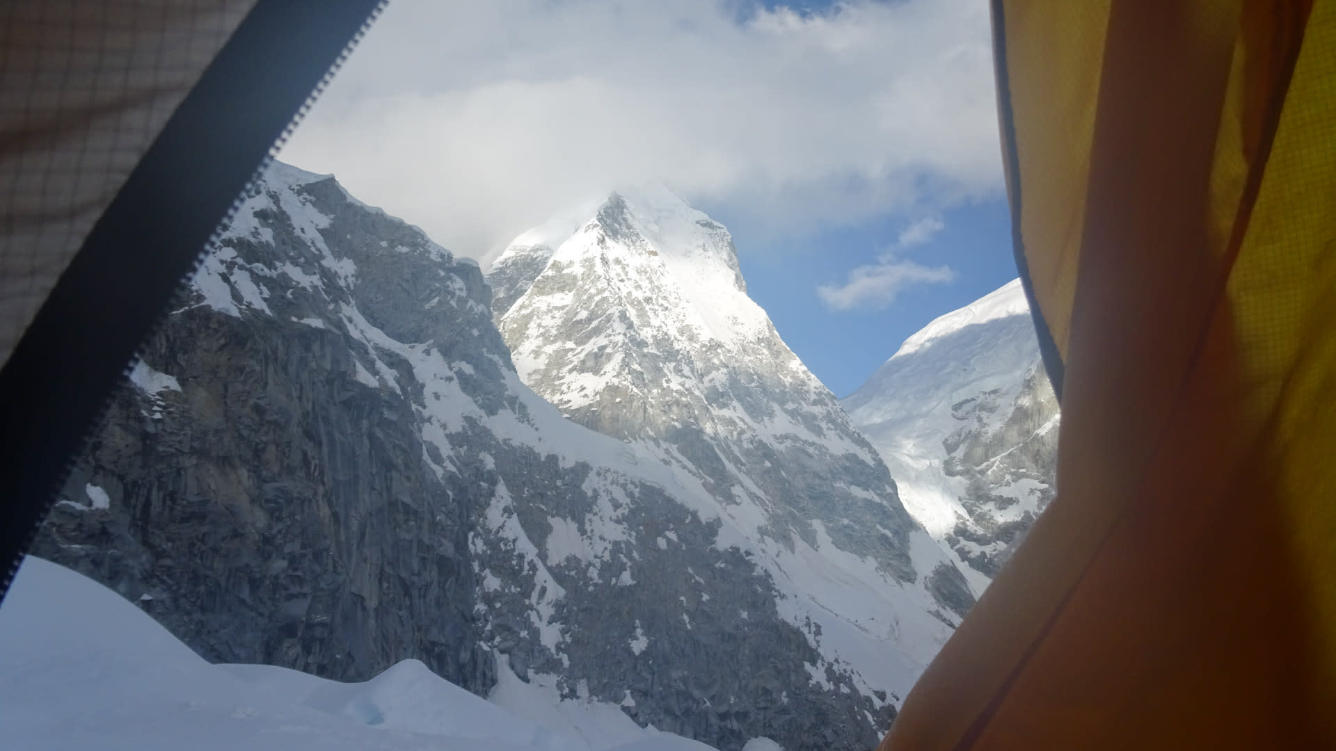 Expedition in Peru: Blick aus geöffnetem Zelt auf einen vergletscherten Hochgebirgsgipfel mit Steilwänden.