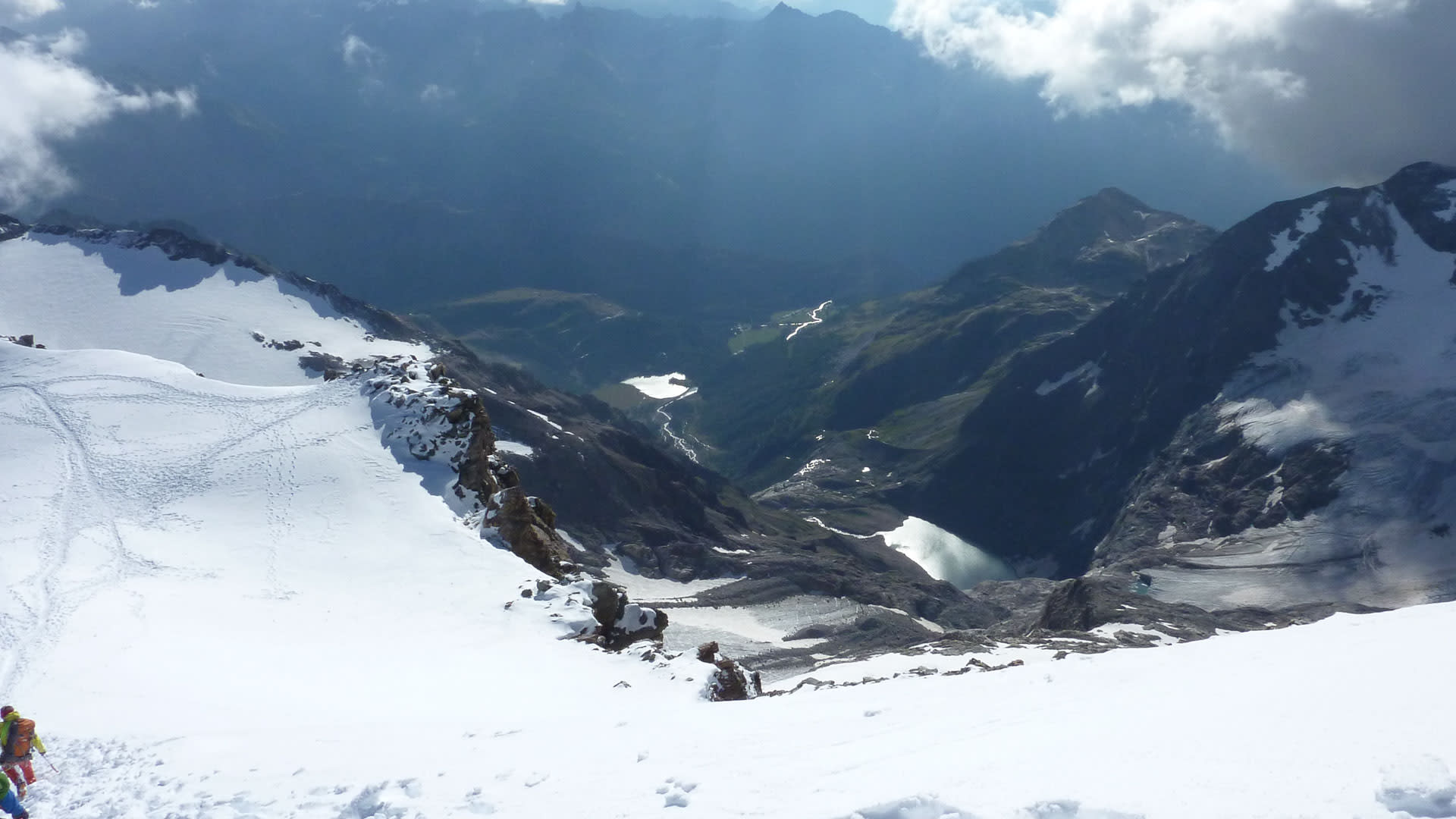 Hochtour am Piz Palü: Zwei Bergsteiger steigen einen steilen Schneehang ab, im Hintergrund öffnet sich das Tal mit Gletscherbereich.