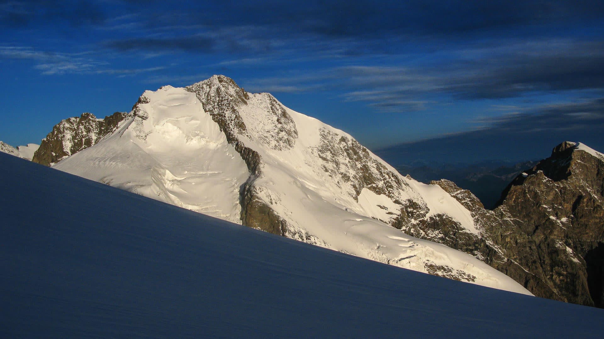 Hochtour am Biancograt des Piz Bernina bei Morgenlicht: felsiger Hauptgipfel mit Schneefeldern und Gletscherflanken.