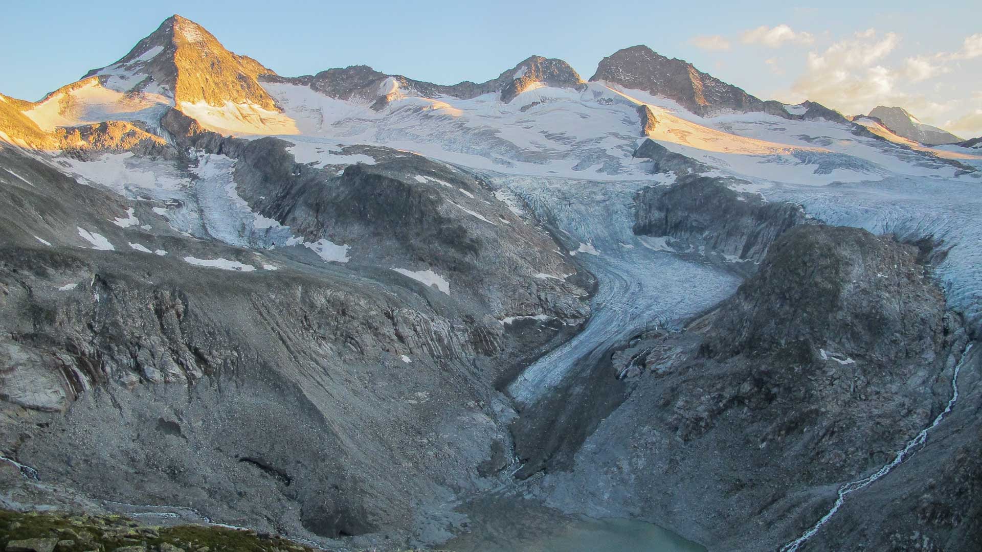 Hochtour auf den Großvenediger: weites Gletscherbecken mit Moränen, Gletschersee und Gipfeln im Alpenglühen der Hohen Tauern.