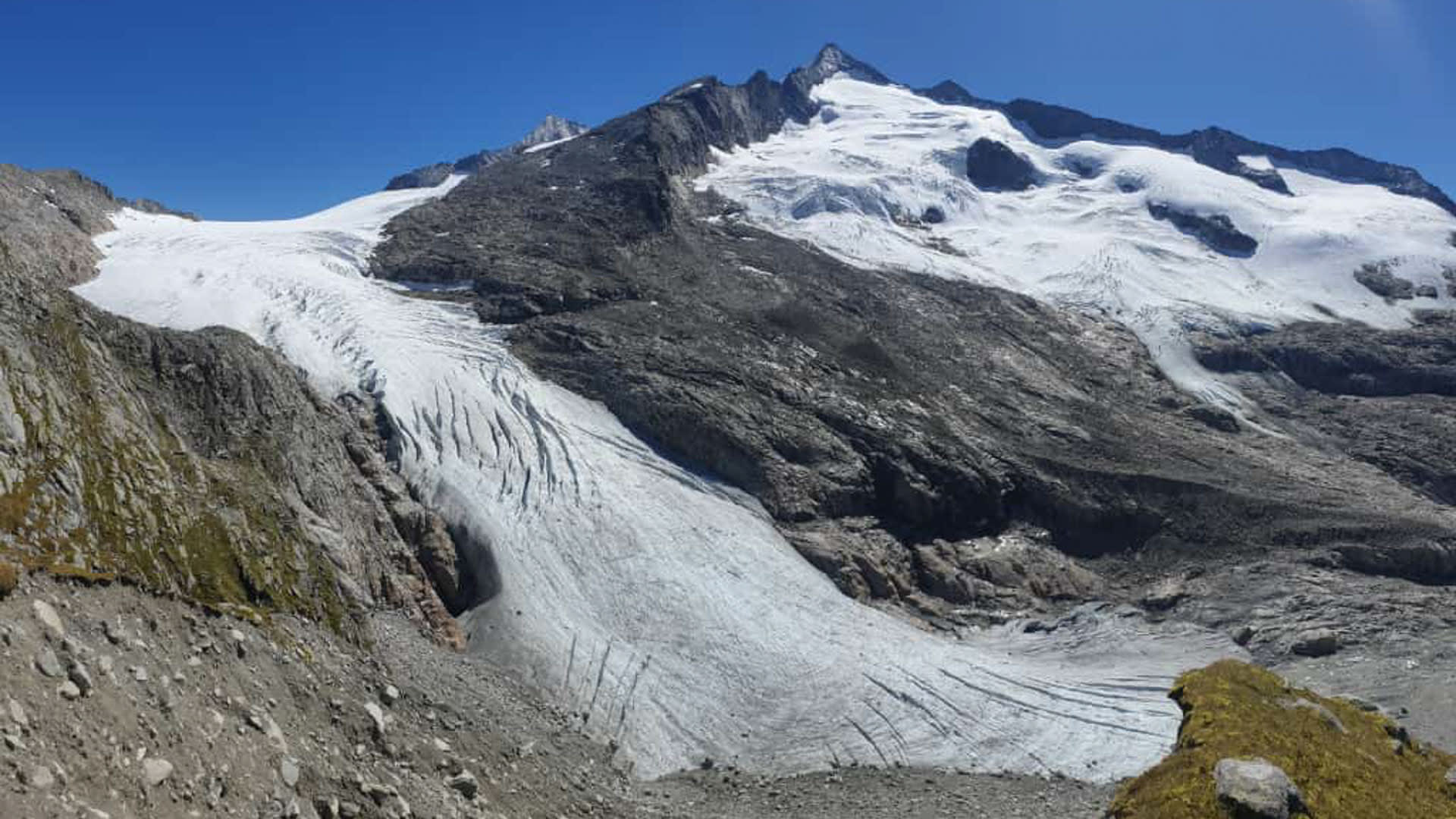 Hochtour am Obersulzbachkees: Gletscherzunge mit Eishöhle und Ogiven vor dem Großvenediger-Massiv.