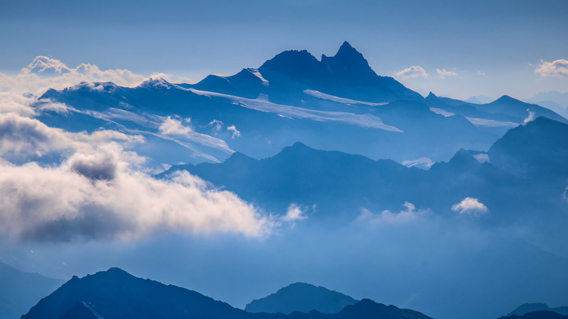 Hochtour in den Hohen Tauern: Weitblick auf gestaffelte Bergketten mit vergletschertem Hauptgipfel und Luftperspektive.
