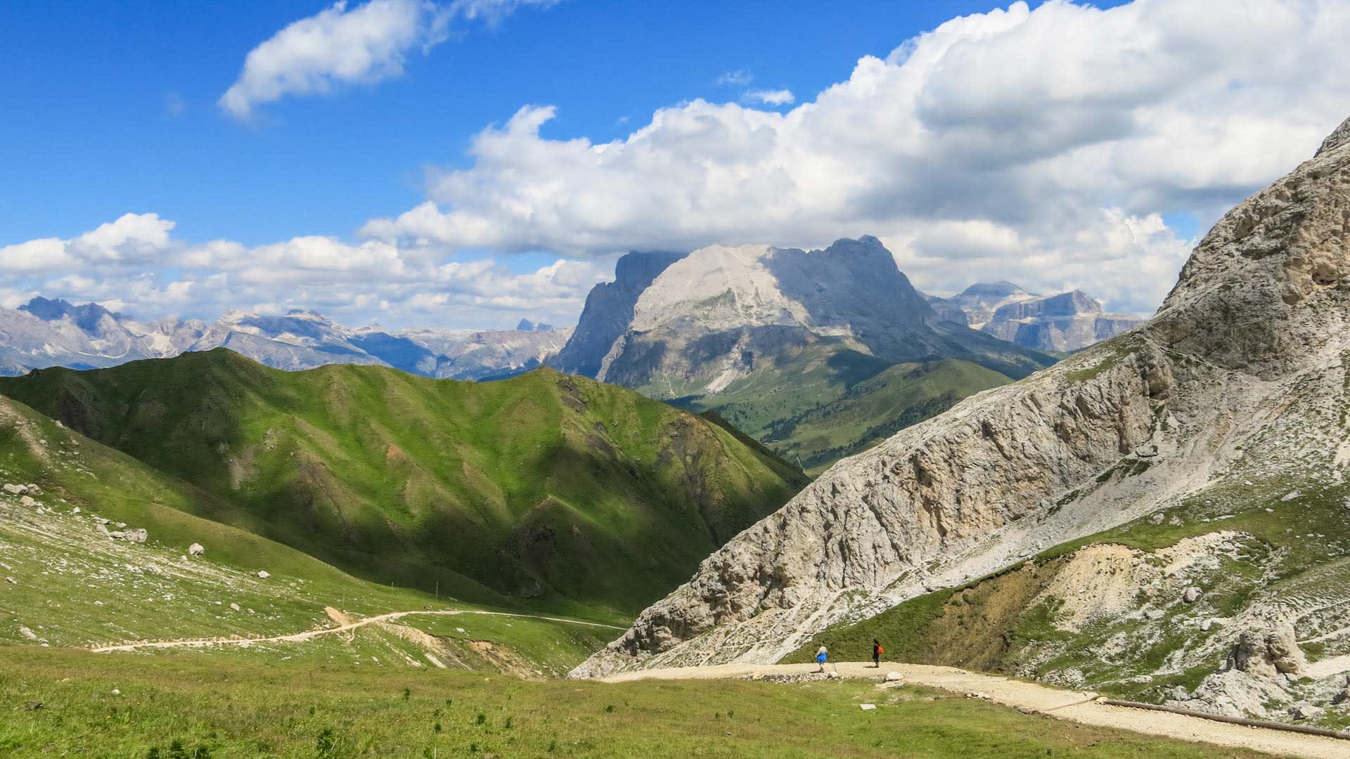 Wandern vom Langkofel zur Tierser Alp: zwei Kletterer auf Almweg vor Dolomitenkulisse in Südtirol.