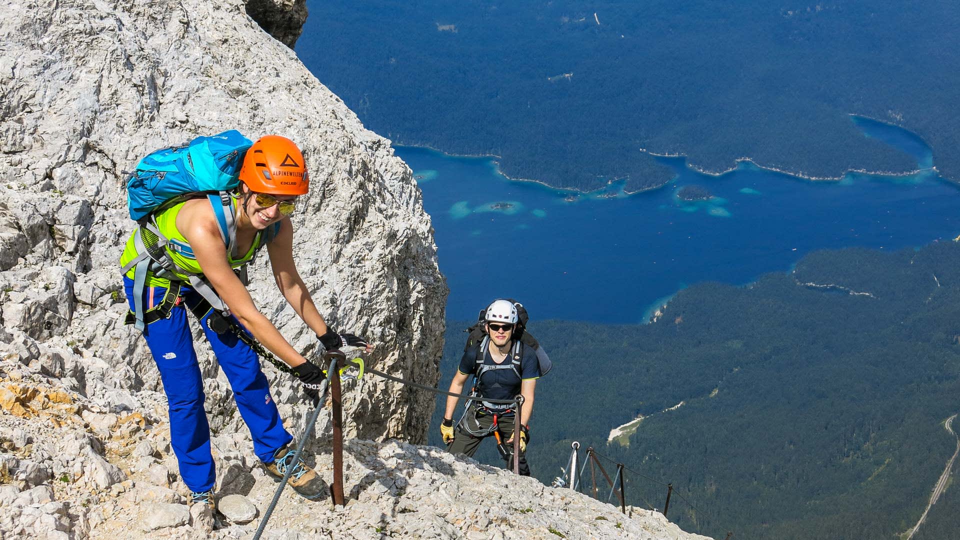 Klettersteig im Höllental: zwei Klettersteiggeher an Metallbolzen mit Tiefblick auf den See.