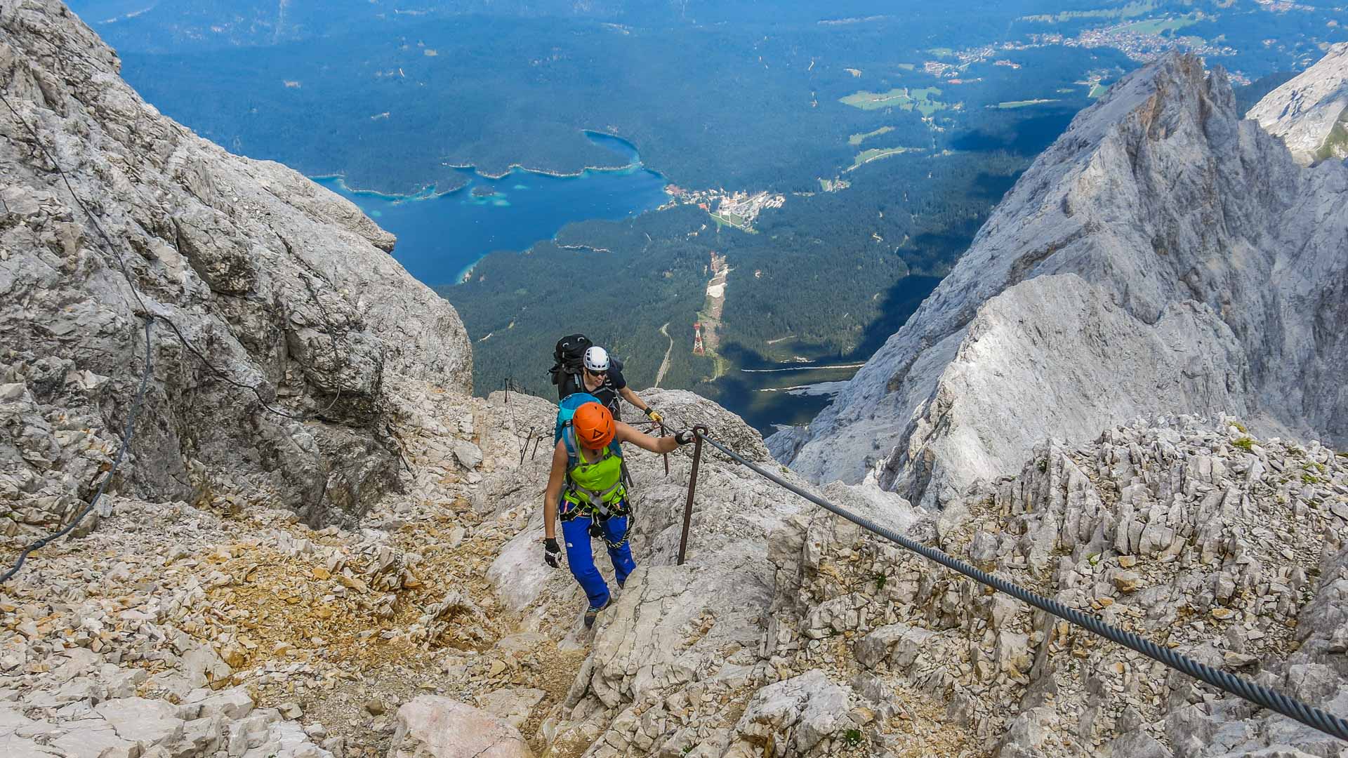 Klettersteig auf die Zugspitze: zwei Klettersteiggeher am Drahtseil über Kalkfels mit Talblick.