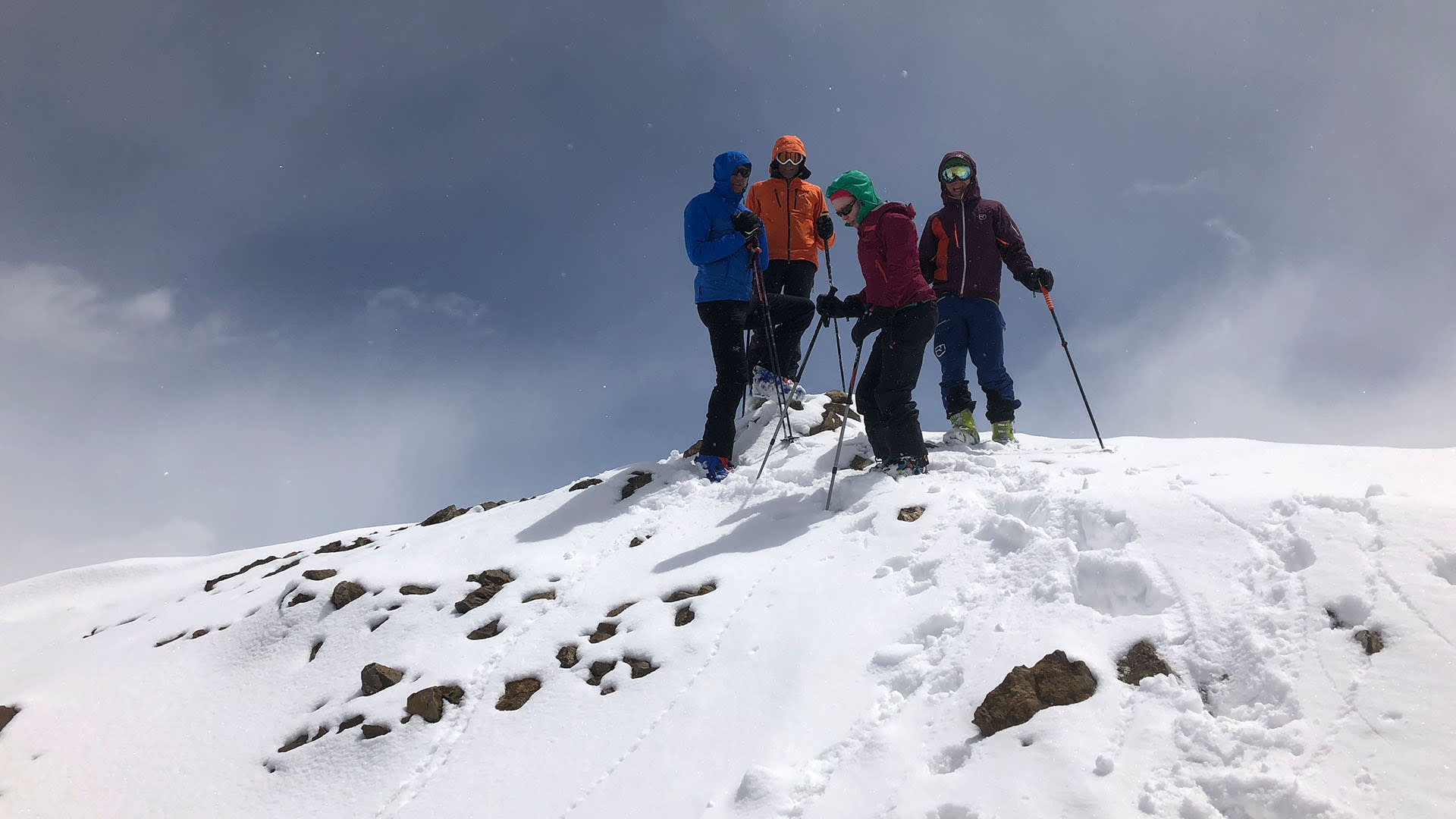 Skitour auf dem Damavand im Iran: vier Skitourengeher mit Ski und Stöcken posieren auf dem schneebedeckten Gipfelgrat.