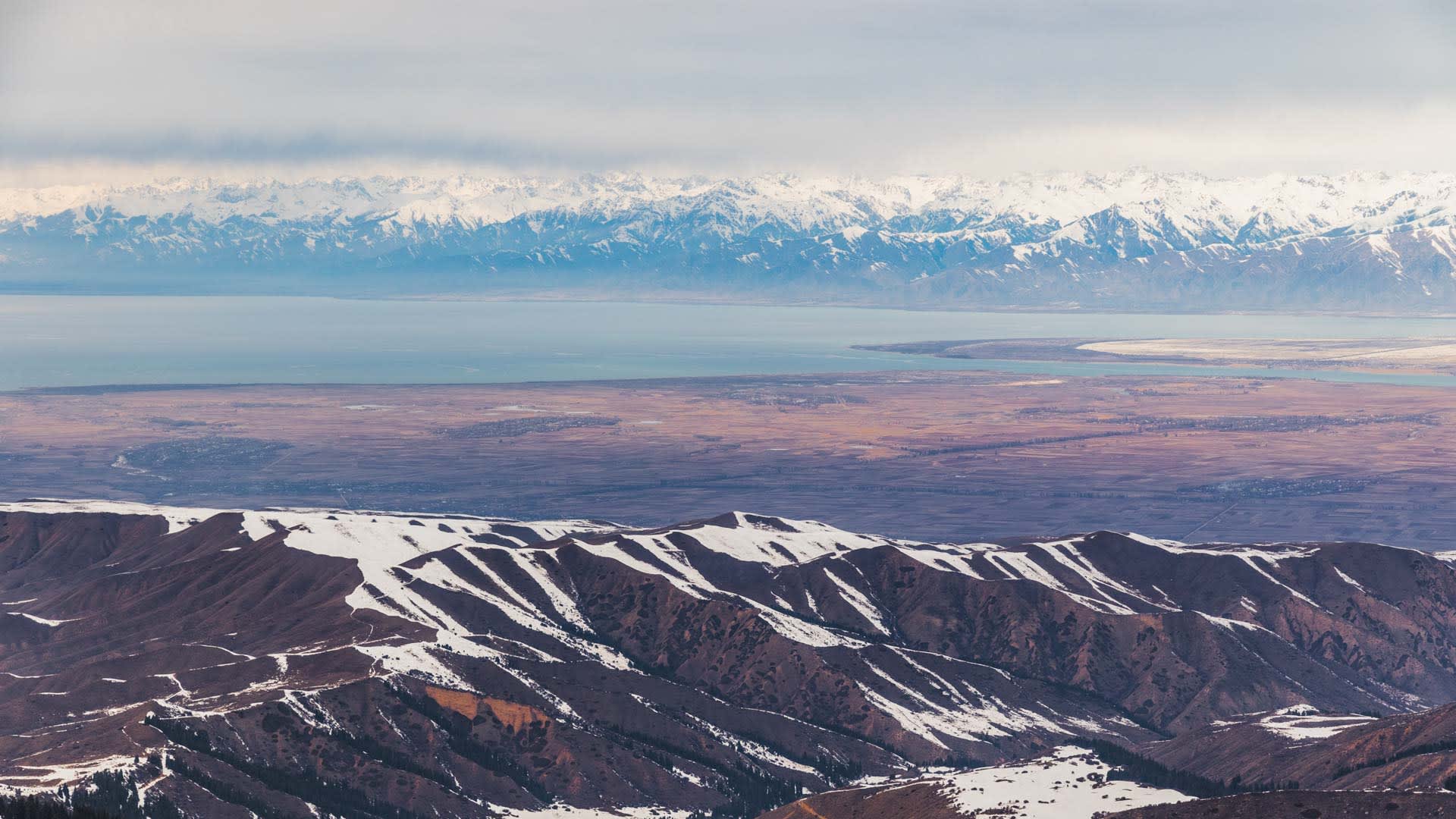 Skitour im Karakol-Gebiet mit Weitblick über den Issyk-Kul und schneebedeckte Hochgebirgszüge Kirgistans.